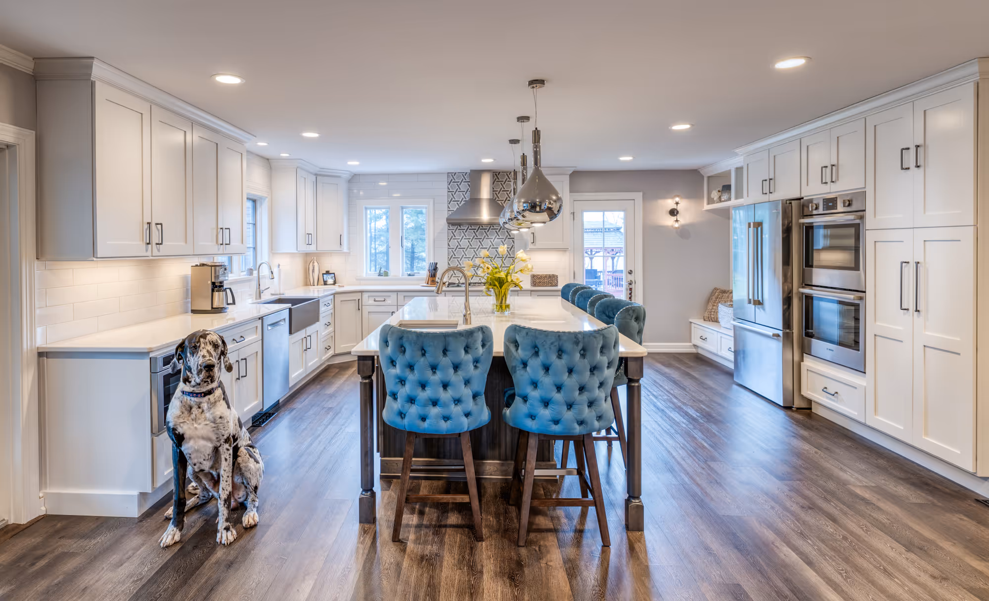 Modern kitchen in Marysville, PA featuring blue tufted stools, stainless steel appliances, and elegant decor.