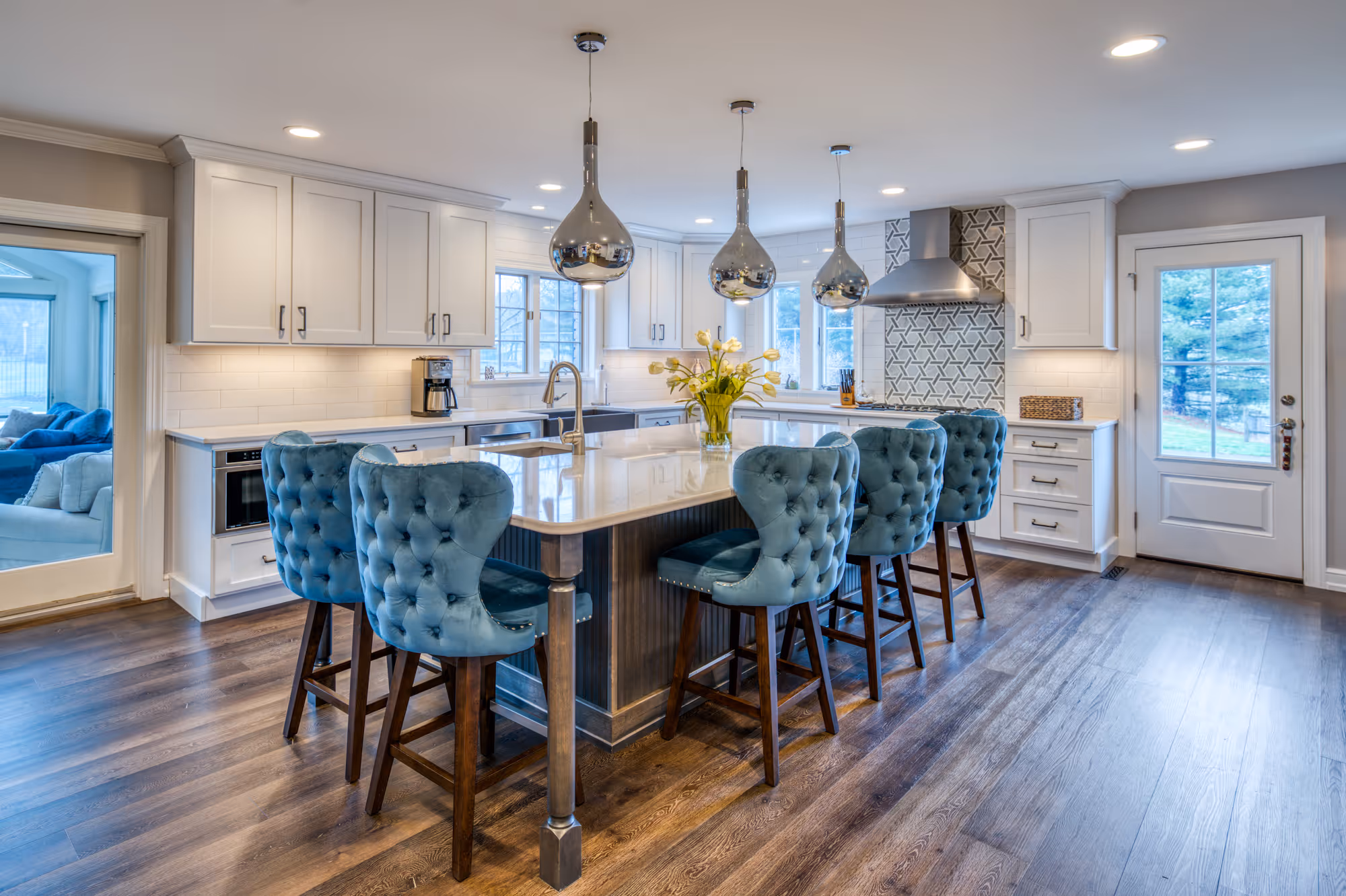 Modern kitchen in Marysville, PA with blue tufted island seating, sleek white cabinetry, and ample natural light.