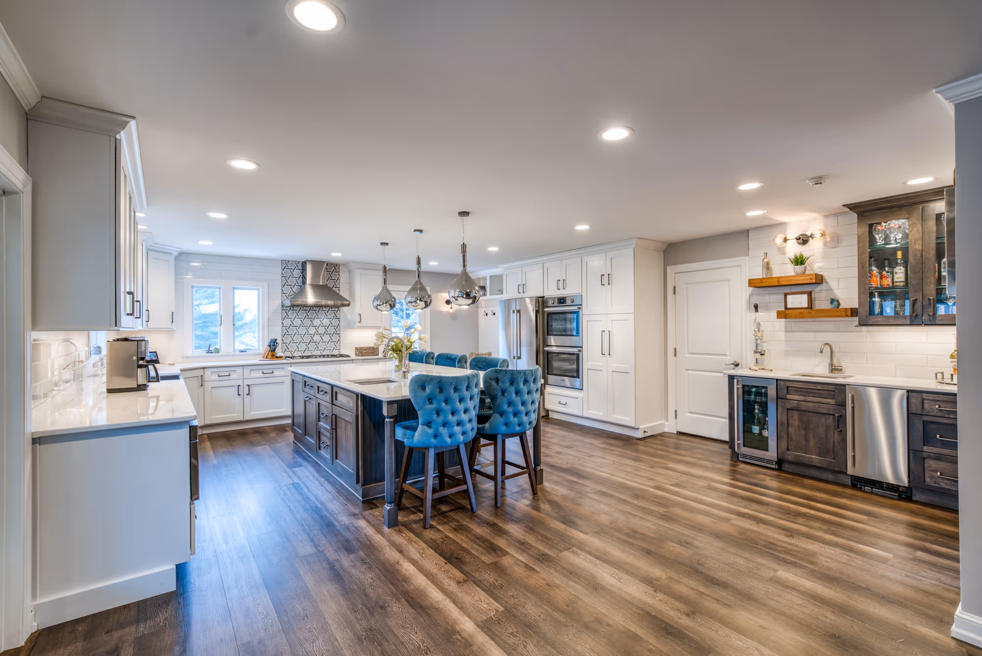 Modern kitchen design featuring white cabinetry, a large island with blue tufted chairs, and a stylish patterned backsplash in marysville, pa