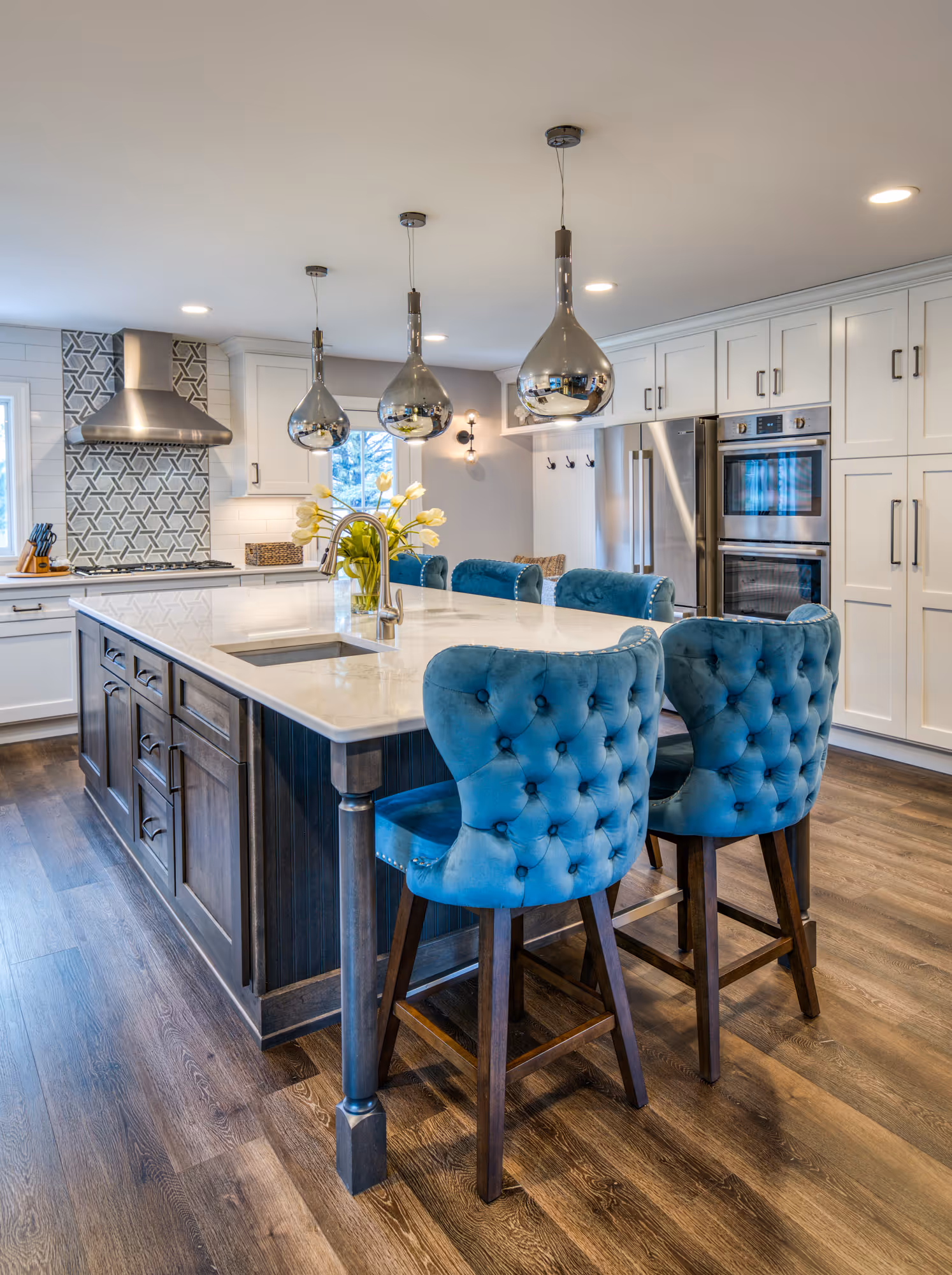 Modern kitchen remodel in Marysville, PA featuring an island with blue tufted stools and a sleek countertop.