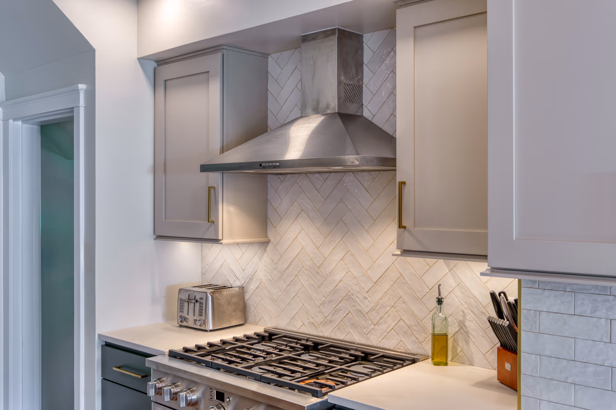 Modern kitchen with a stainless steel hood, herringbone backsplash, and gray cabinetry in harrisburg, pa.