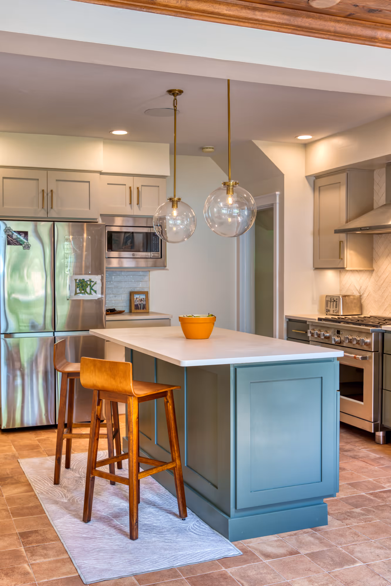 Modern kitchen with teal cabinetry, wooden bar stools, and stylish pendant lights in Harrisburg, PA.