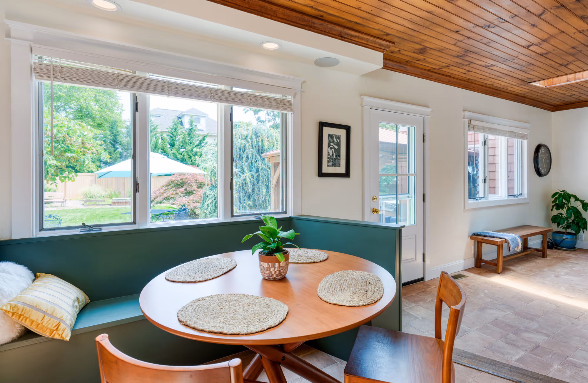 Cozy kitchen with built-in green bench seating and round wooden table in Harrisburg, PA, featuring natural light and outdoor views