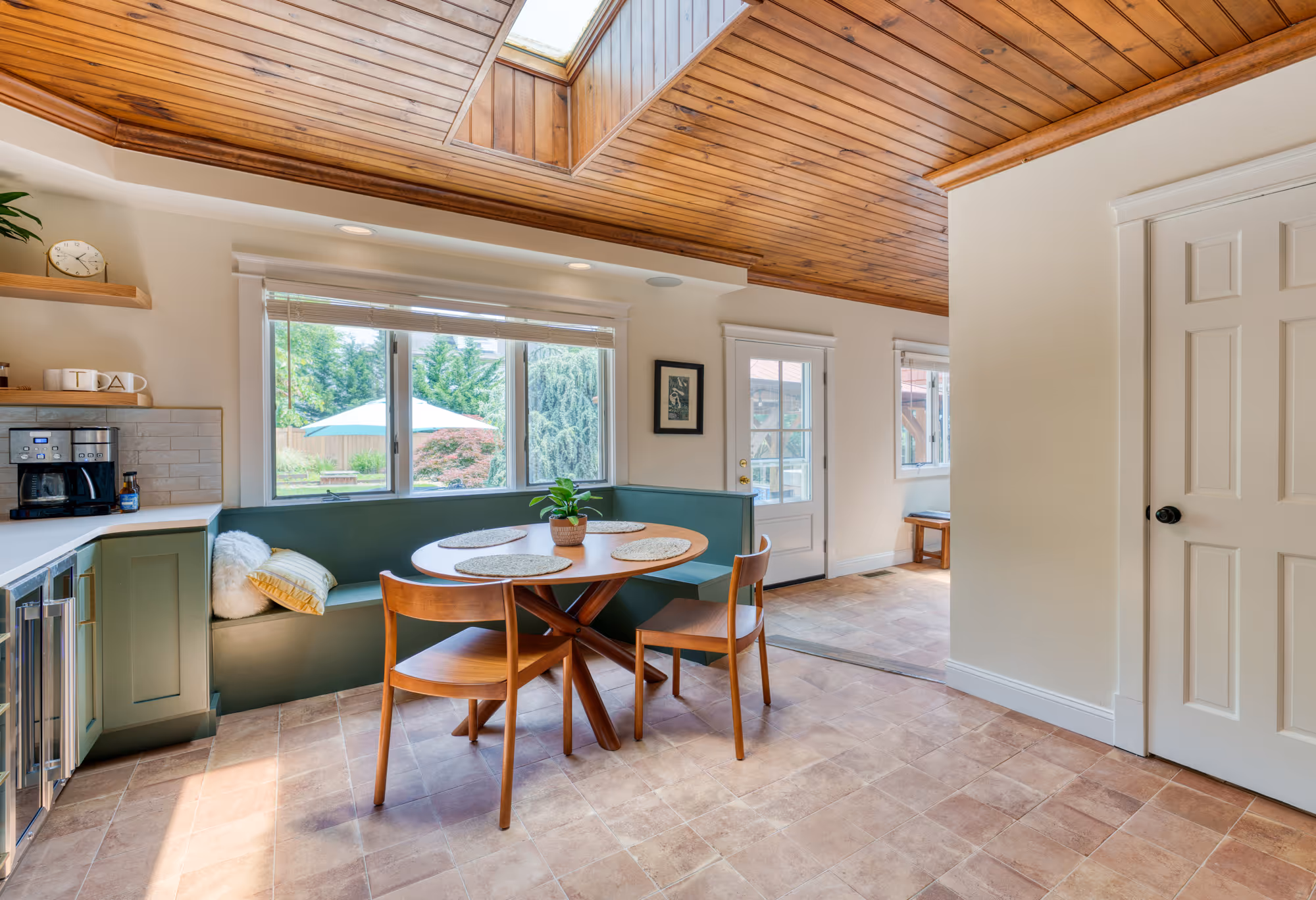 Cozy kitchen in harrisburg, pa featuring a built-in dining area with wooden seating and large windows overlooking greenery.