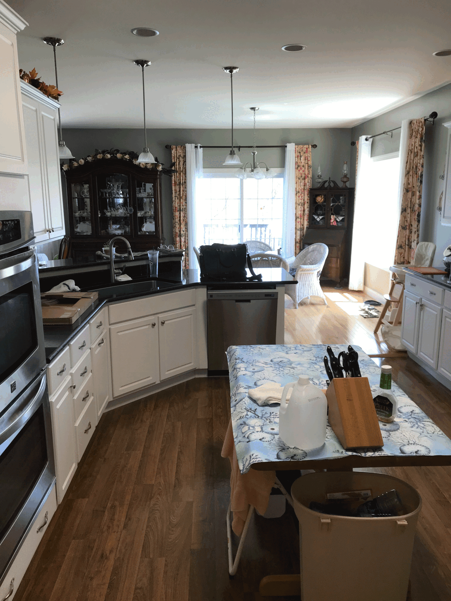Spacious contemporary kitchen in Harrisburg, PA featuring white cabinets, a wooden table, and pendant lights.