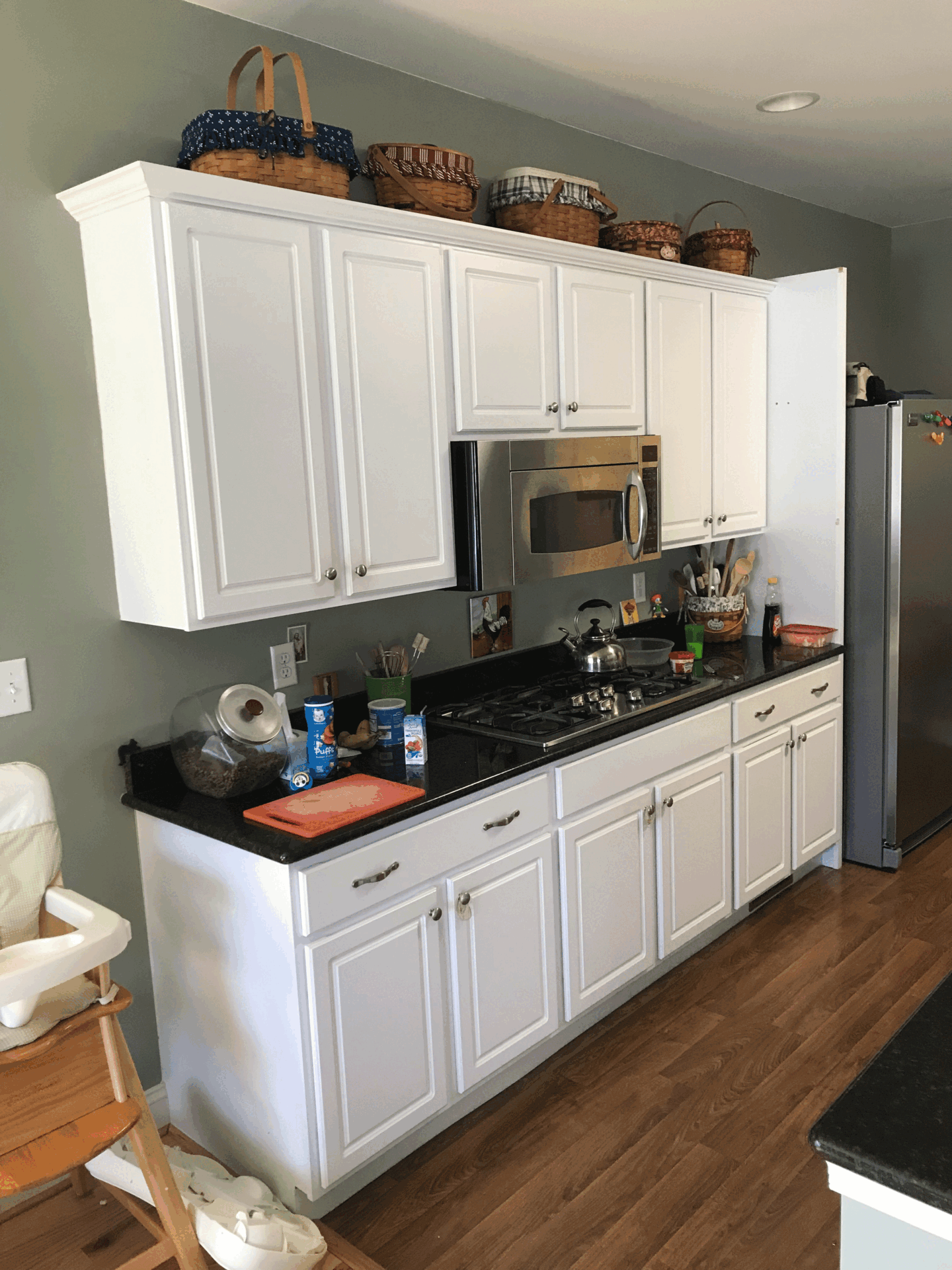Modern kitchen with white cabinetry, black countertops, and wood flooring in Harrisburg, PA.