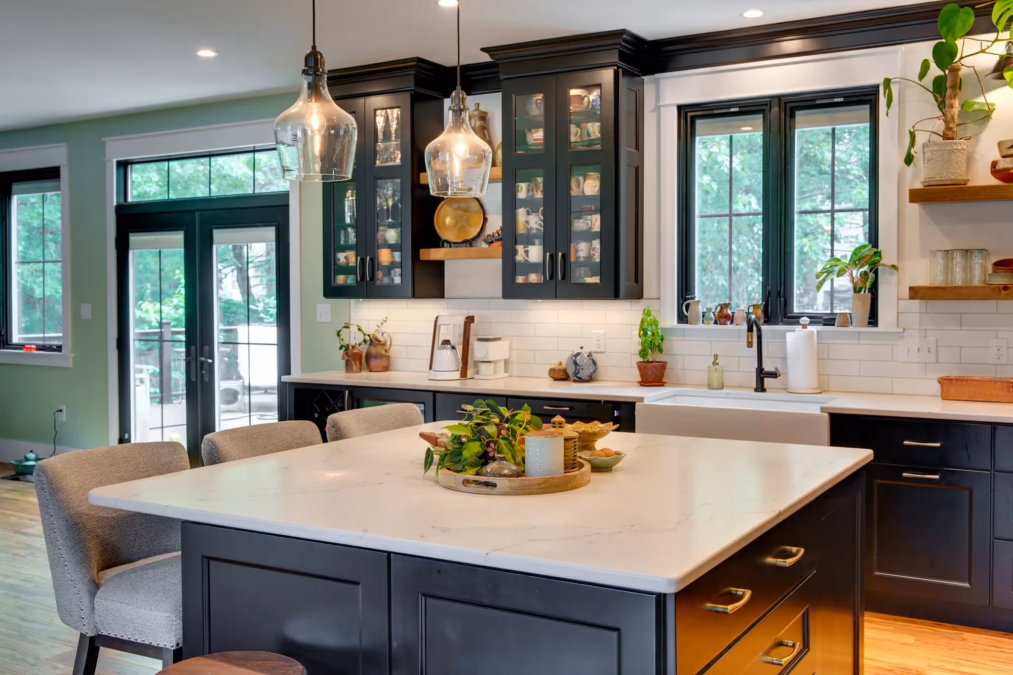 Modern kitchen with island, sleek countertops, and large windows.