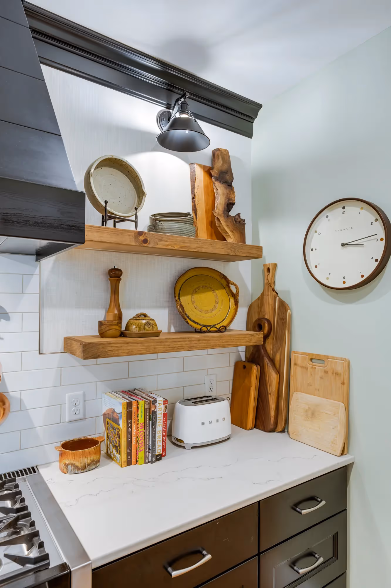 Kitchen with open shelving, decorative kitchenware, and a modern clock.