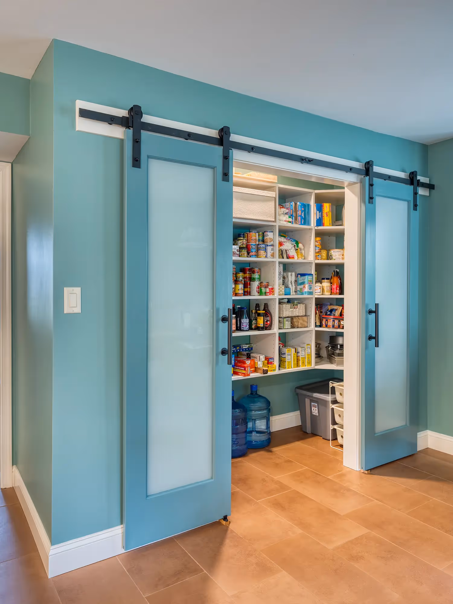 Sliding pantry doors in a kitchen with glass shelves