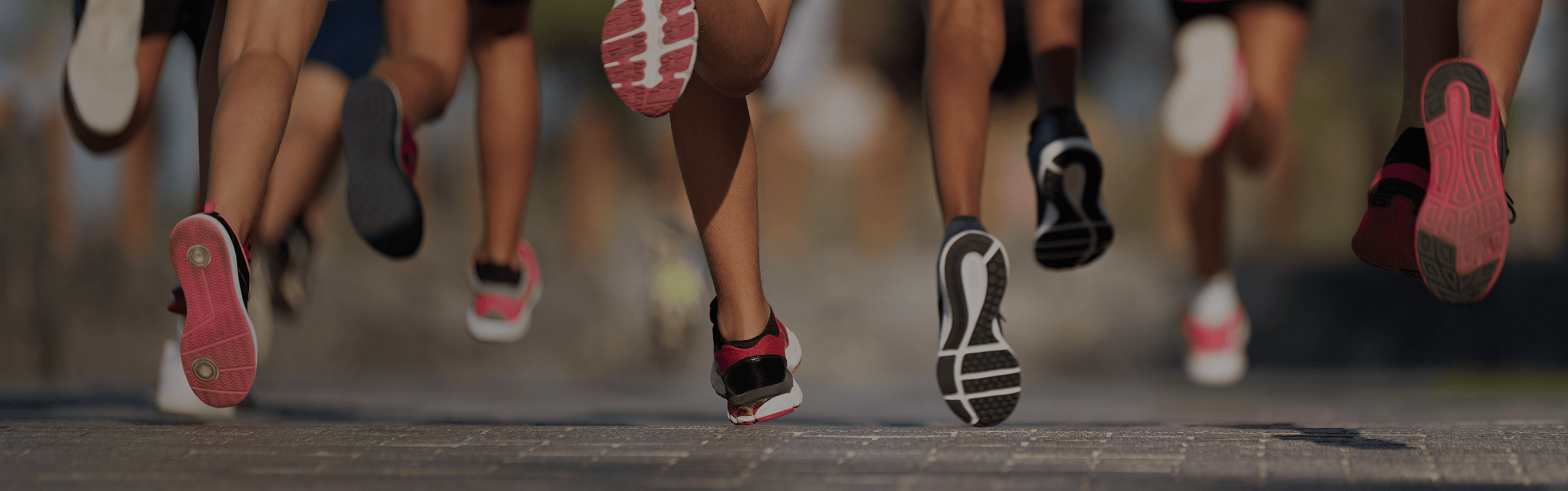 Close-up of runners' legs and feet on an asphalt road during a marathon race.