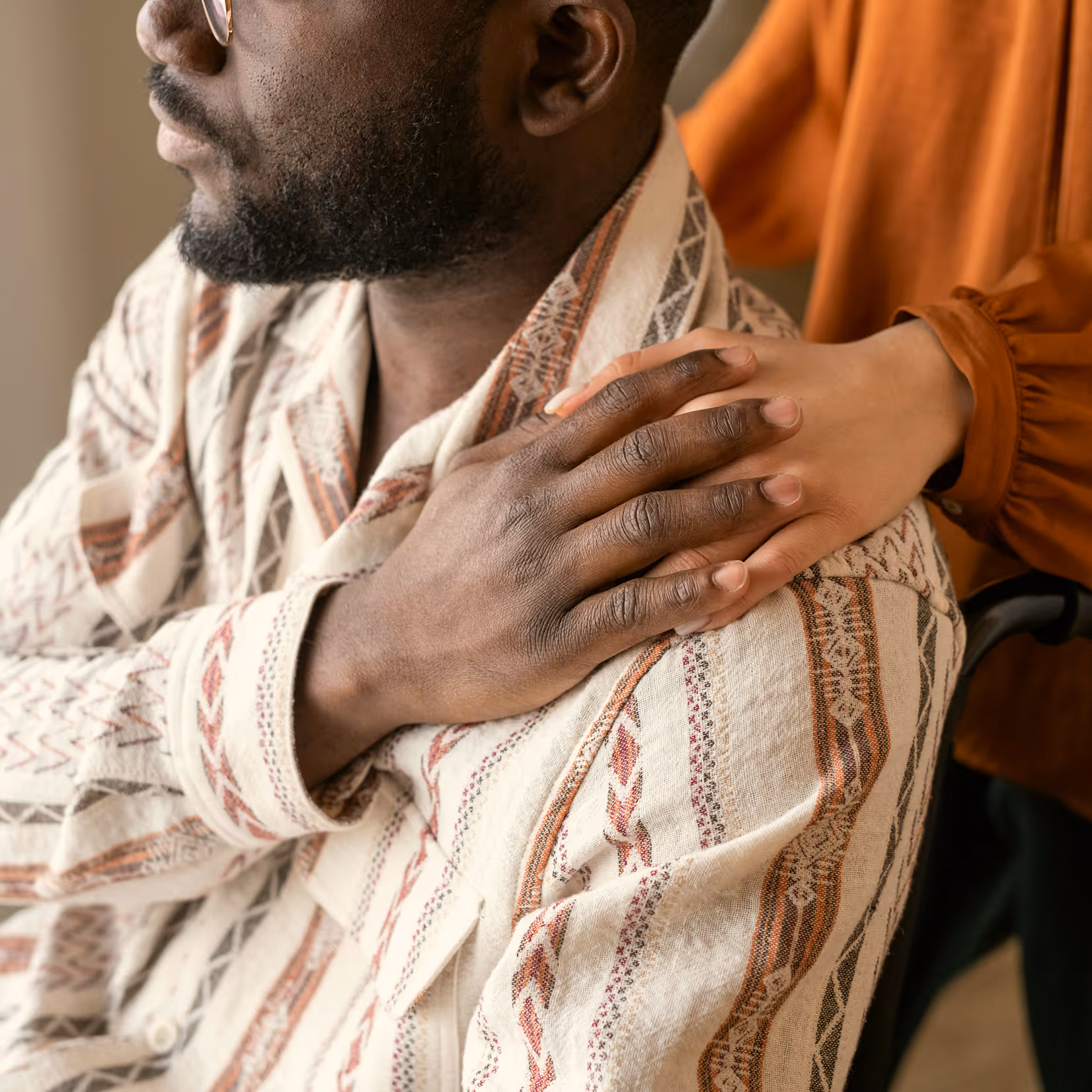 Close-up of a hand resting on another person’s shoulder in a supportive gesture.