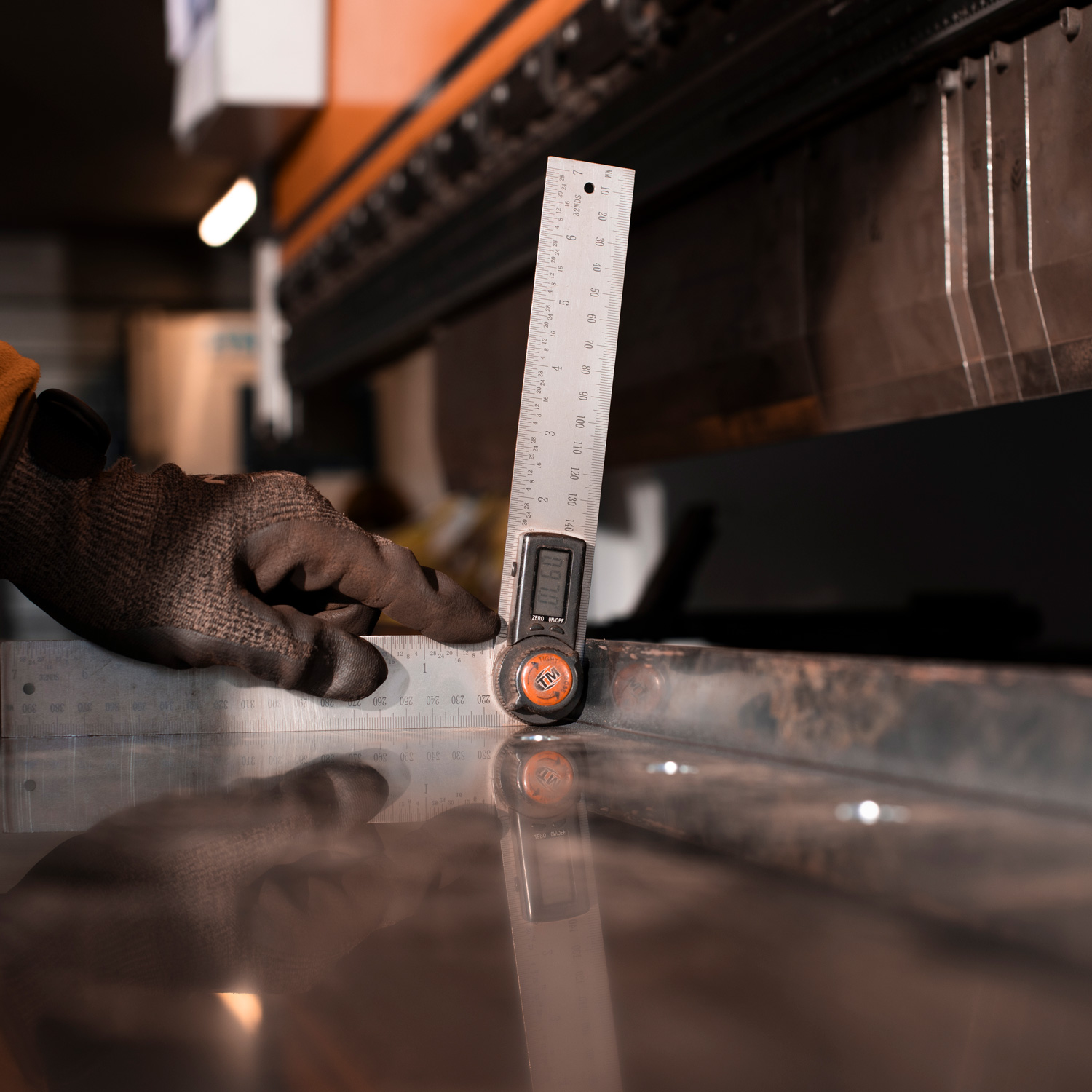 Thermal Pro worker holding a digital angle ruler against a fold sheet of steel.