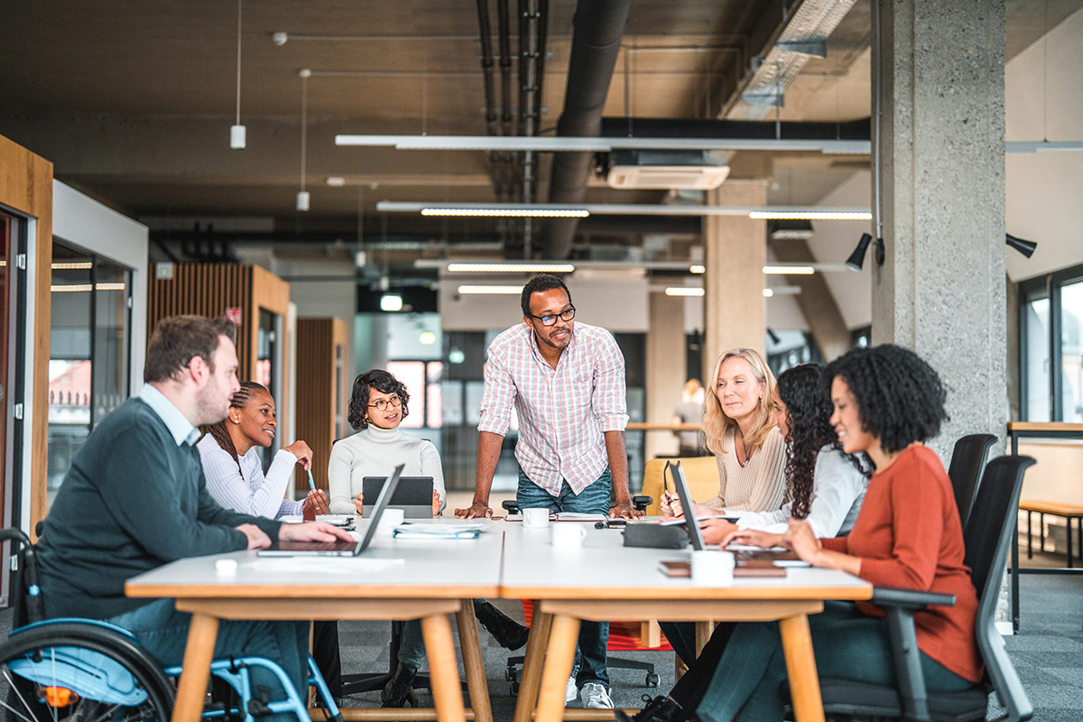 Diverse group of six people having a meeting around a table in a modern office.