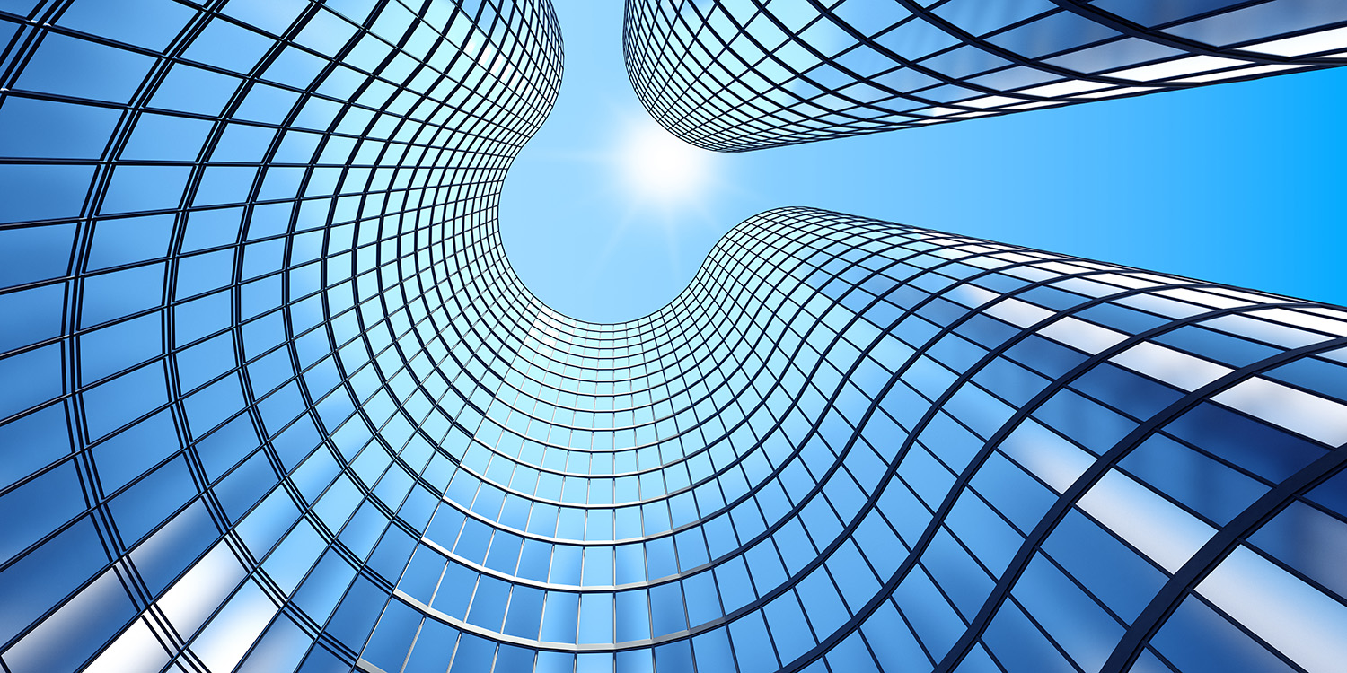 Curved glass skyscrapers with reflective blue windows against a bright blue sky with the sun.