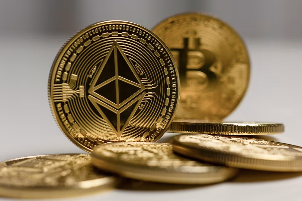 A graphic featuring a golden Ethereum Coin with a Bitcoin in the background, sitting on top of a pile of coins