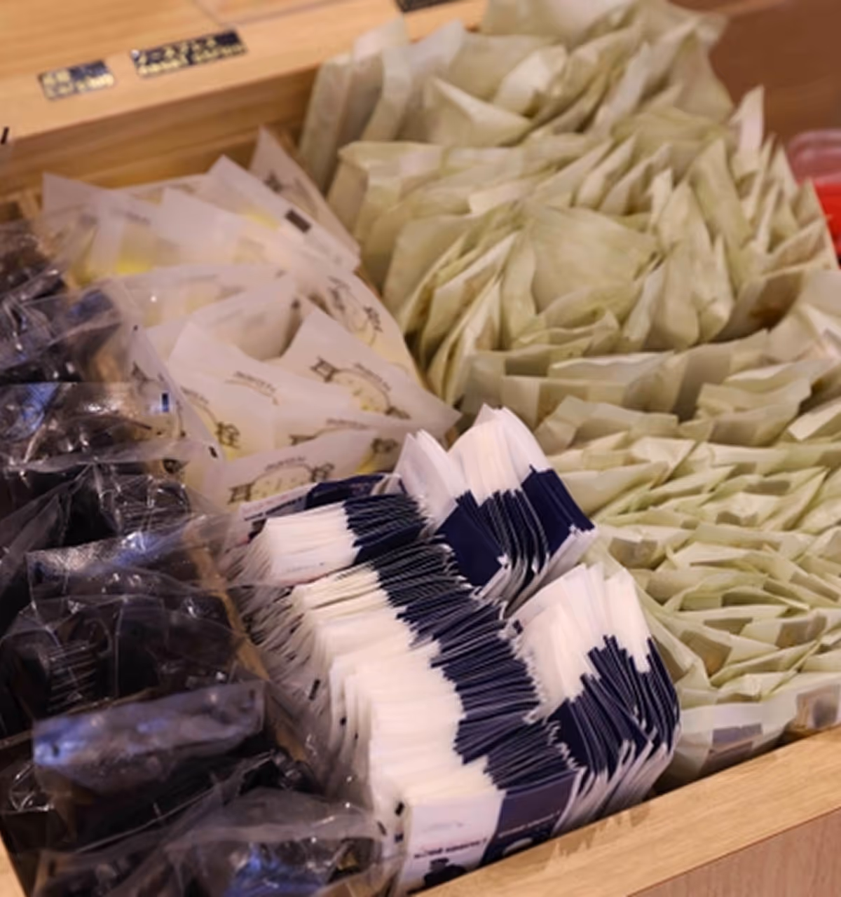 Wooden box containing hotel room amenities such as toothbrush, razor, and hair ties, neatly arranged.