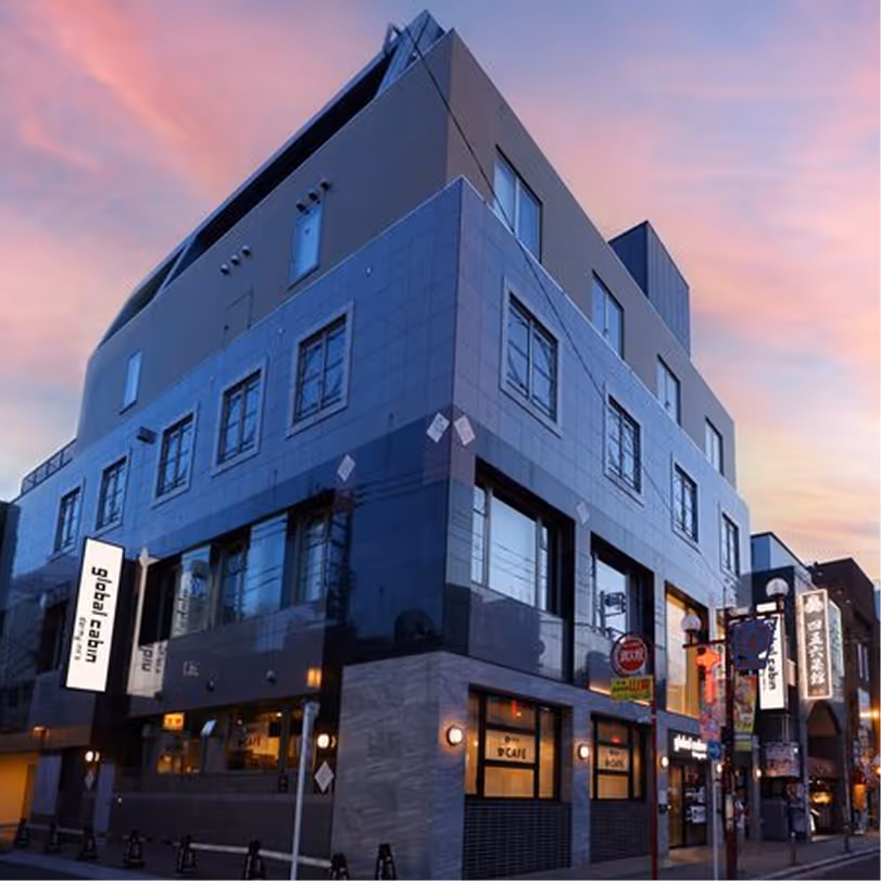 Modern multi-story building with dark exterior and illuminated global cabin sign at dusk.