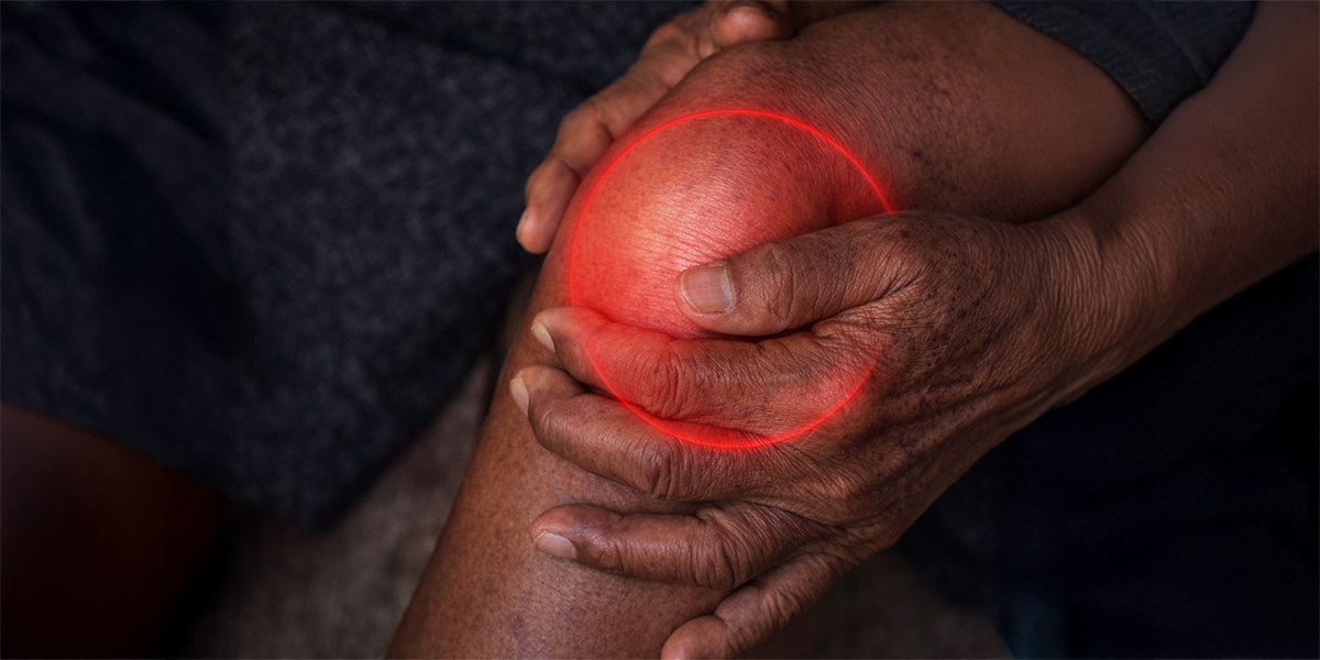 Close-up of a person holding a painful knee joint with a highlighted red inflammation area representing rheumatic disease and joint inflammation