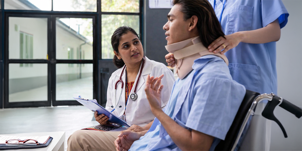 Doctor consulting injured patient wearing neck brace in wheelchair during post-accident recovery care