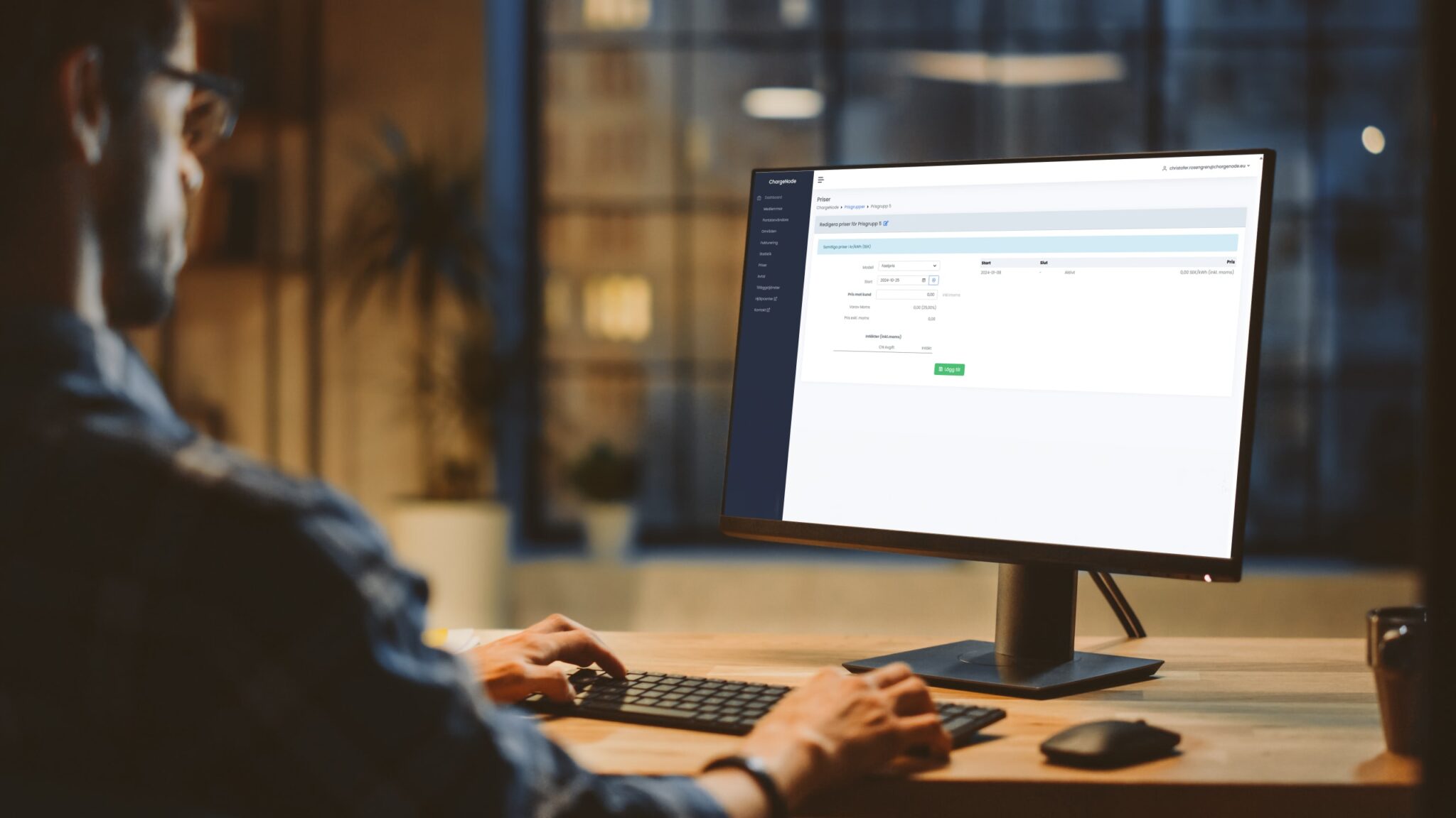 Person som arbetar på en dator med en ChargeNode-prisinställningspanel på skärmen i ett kontorsrum.