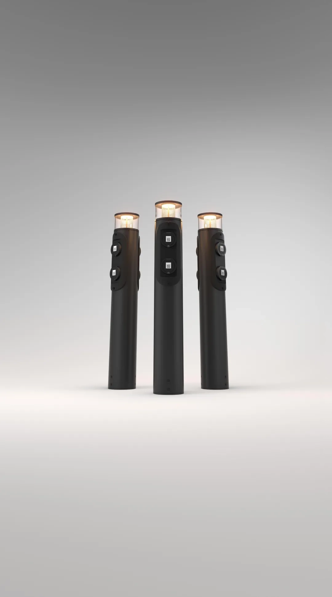 Tre svarta, cylindriska laddstolpar med ljus upptill och dubbla uttag på vardera stolpe mot en grå bakgrund.