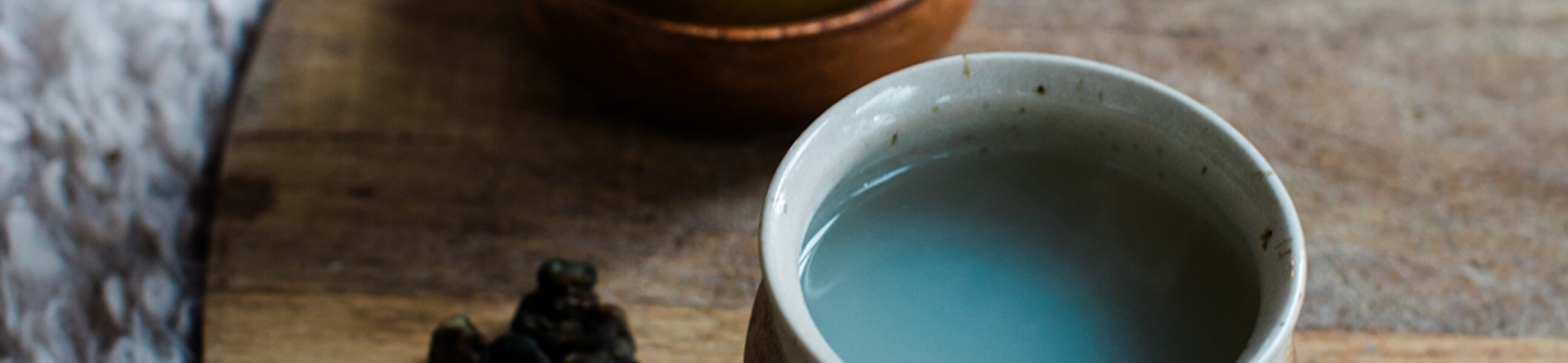 Close-up of a white ceramic cup filled with clear water on a wooden surface.