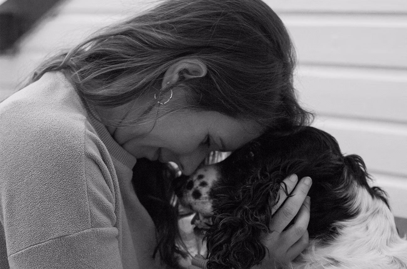 Eine Frau und ein Hund kuscheln Stirn an Stirn.