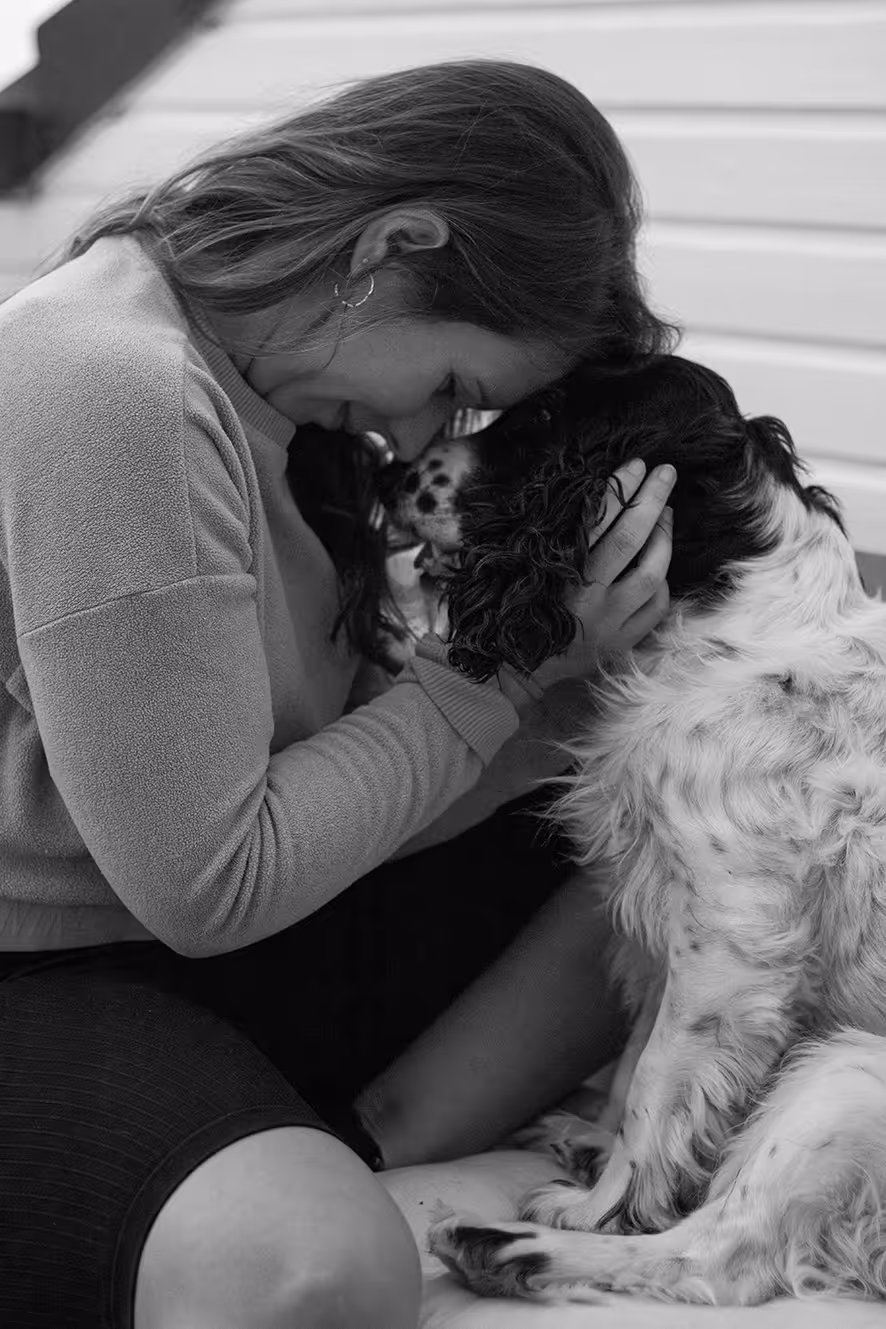 Eine Frau und ein Hund kuscheln Stirn an Stirn.