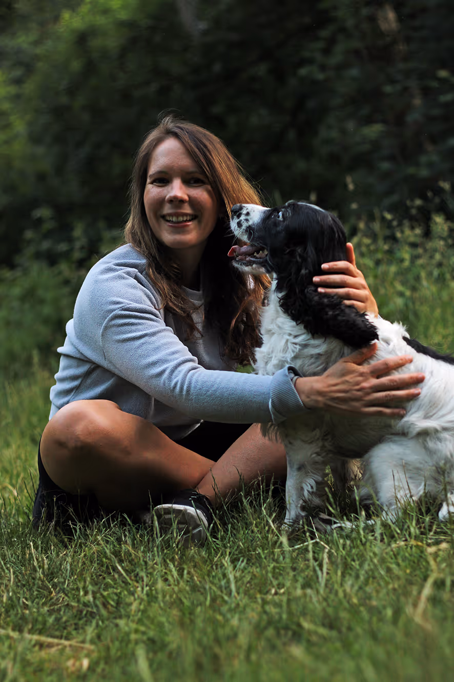 Frau und Hund kuscheln auf der Wiese.