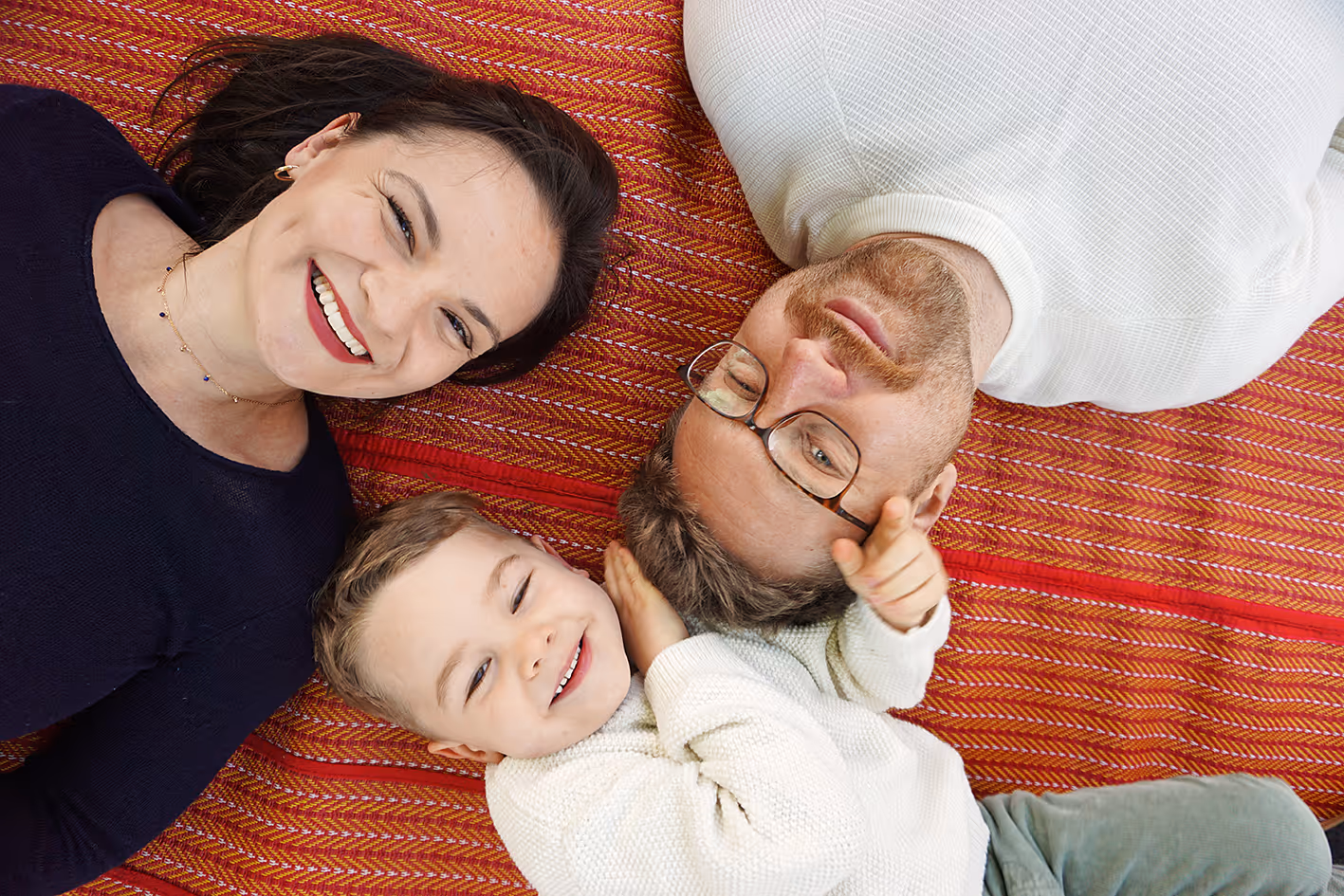Eine Junge Familie lächelt in die Kamera. Mama, Papa und Sohn.