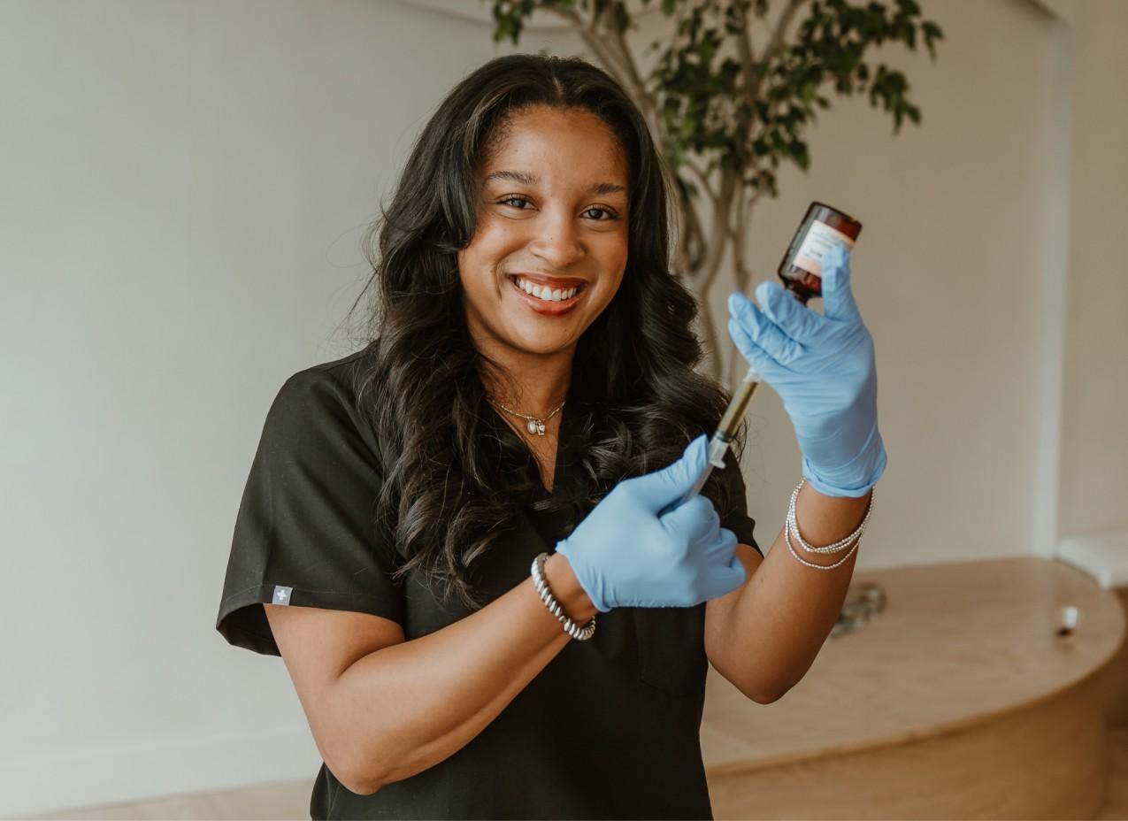 A woman in a black shirt and blue gloves holding a bottle.