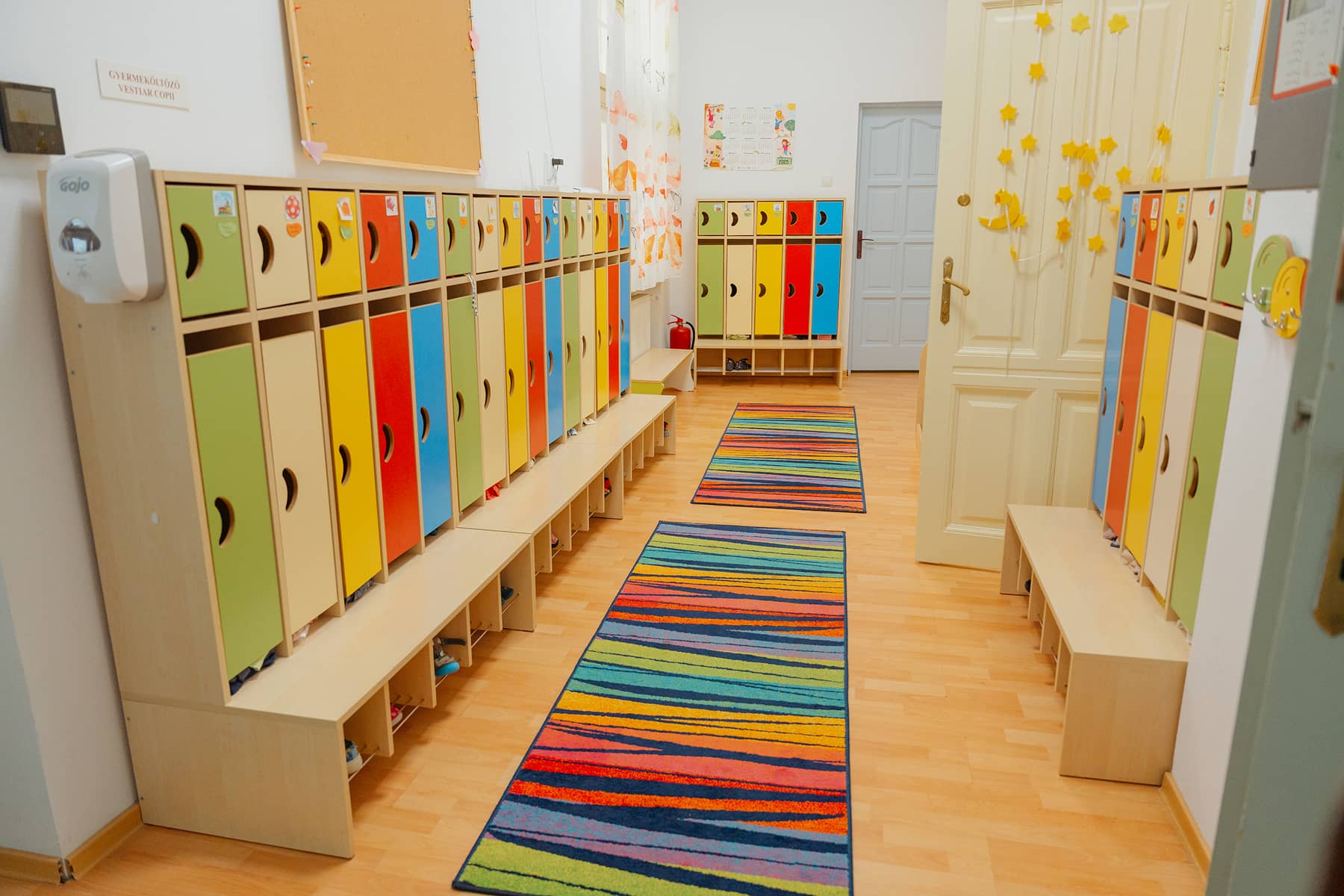 A Szent Imre Óvoda egyik öltözője színes gyermek szekrényekkel és vidám, csíkos szőnyegekkel.