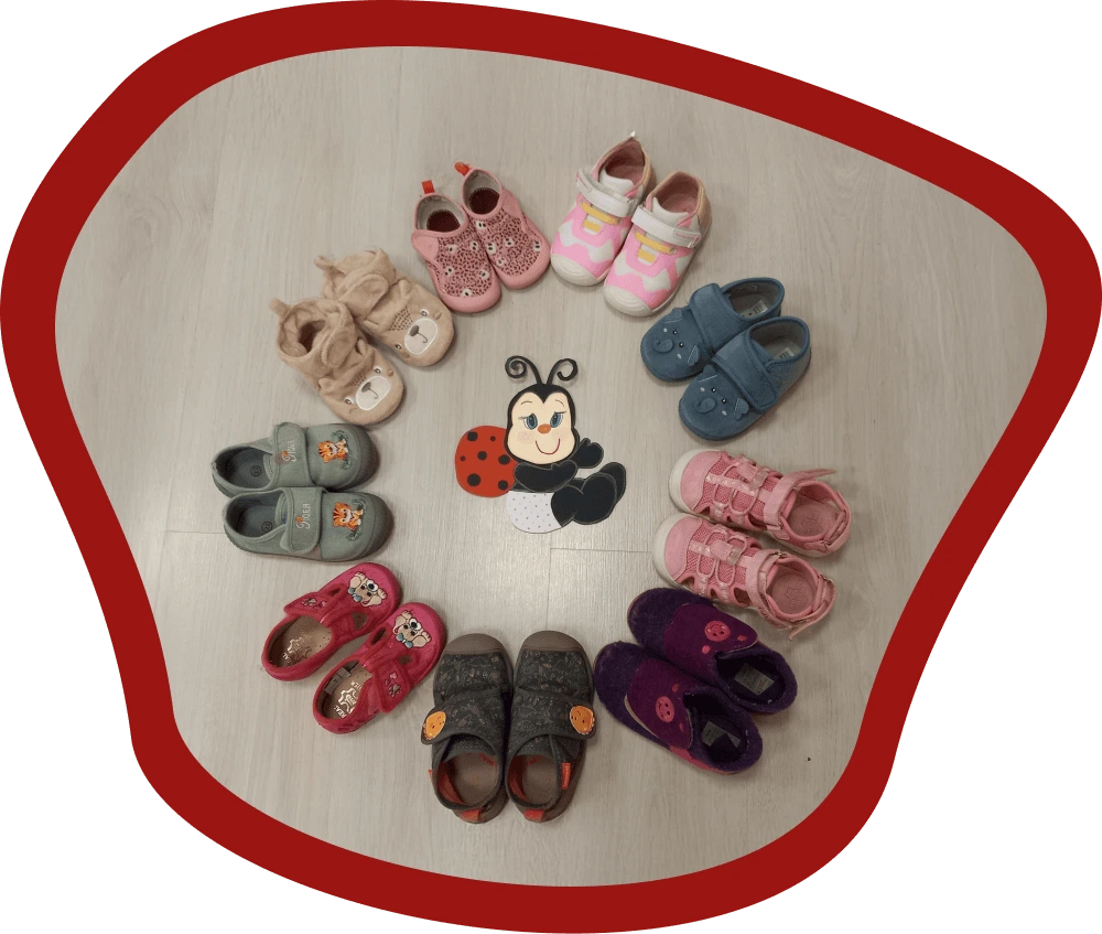 A Katica csoport gyermekei cipői körben elhelyezve, középen egy piros-fekete katicabogár figura látható