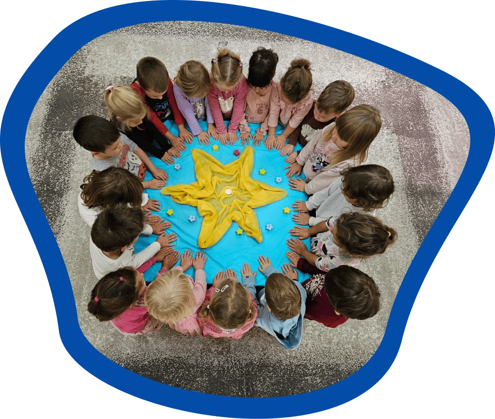 A Csillag csoport gyermekei körben ülnek egy kék kendő körül, amelyen sárga csillag alakú dísz van elhelyezve