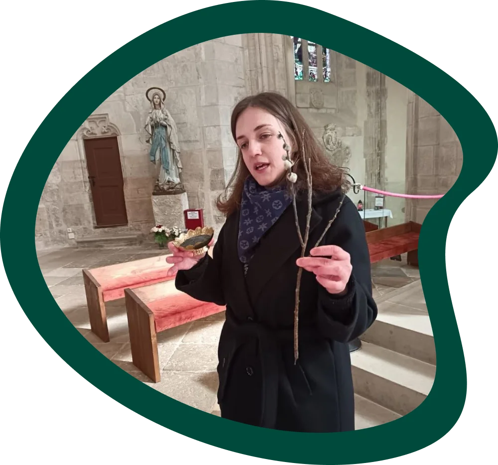 A hitoktató szemléltető bemutatót tart a templomban, barkával és kegytárggyal a kezében.