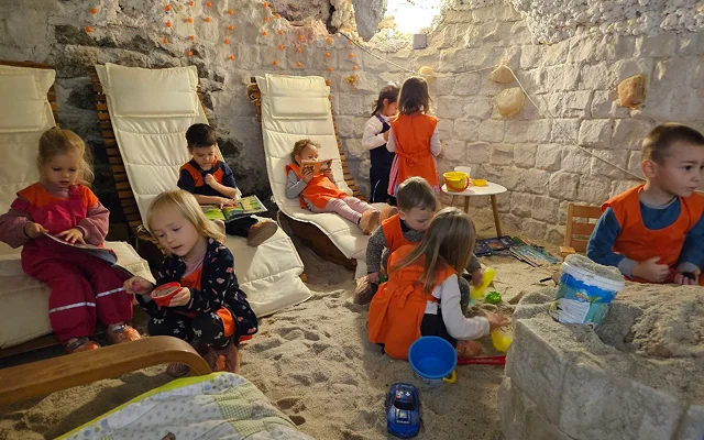 Óvodások a sószobában játszanak, könyveket forgatnak, nézegetnek, nyugágyakon ülve.