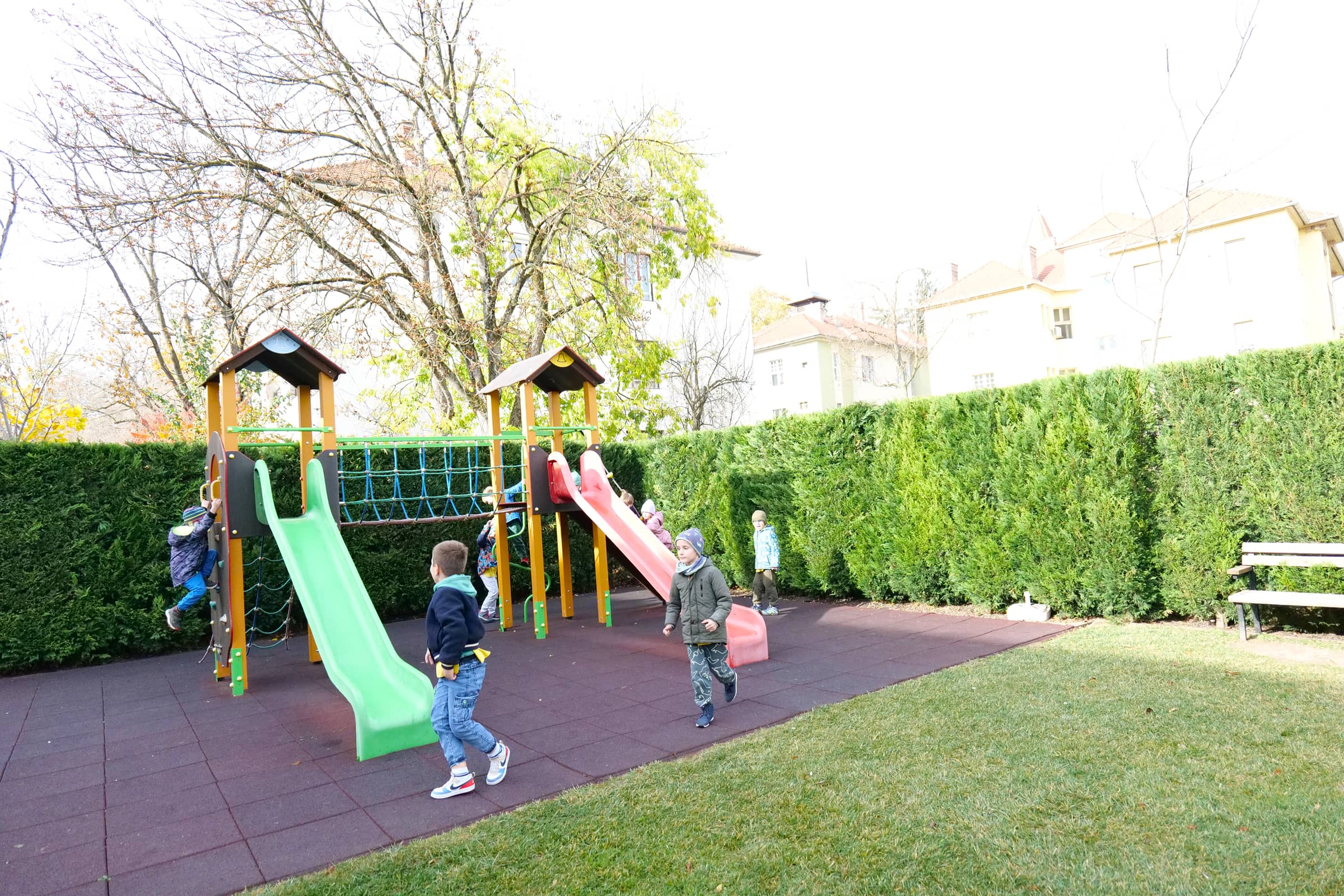Gyerekek szabadtéri játék közben a csúszdás mászókán az óvoda udvarán.