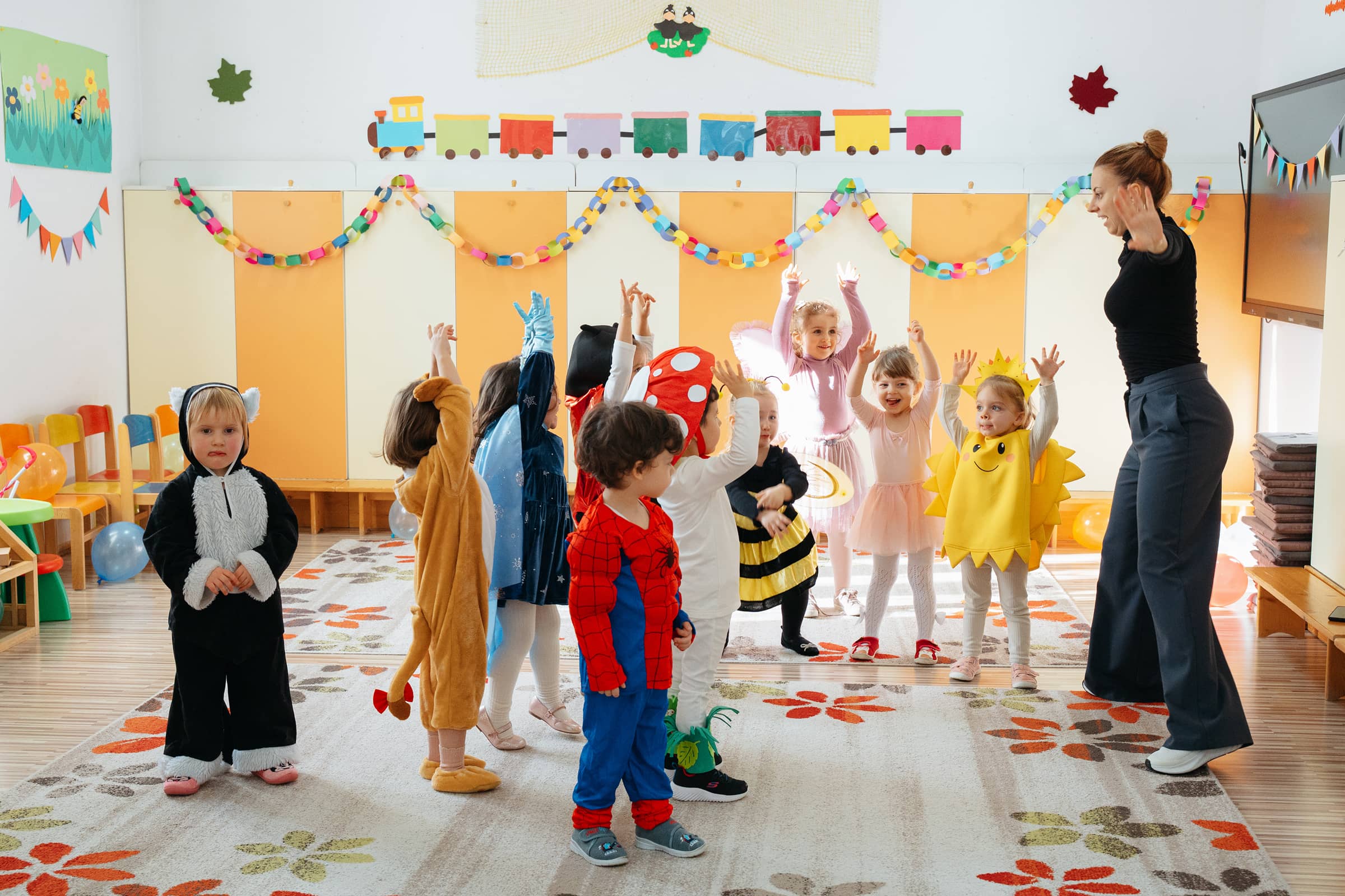 Copii de grădiniță, îmbrăcați în costume de carnaval, participă la un joc de mișcare în grup.