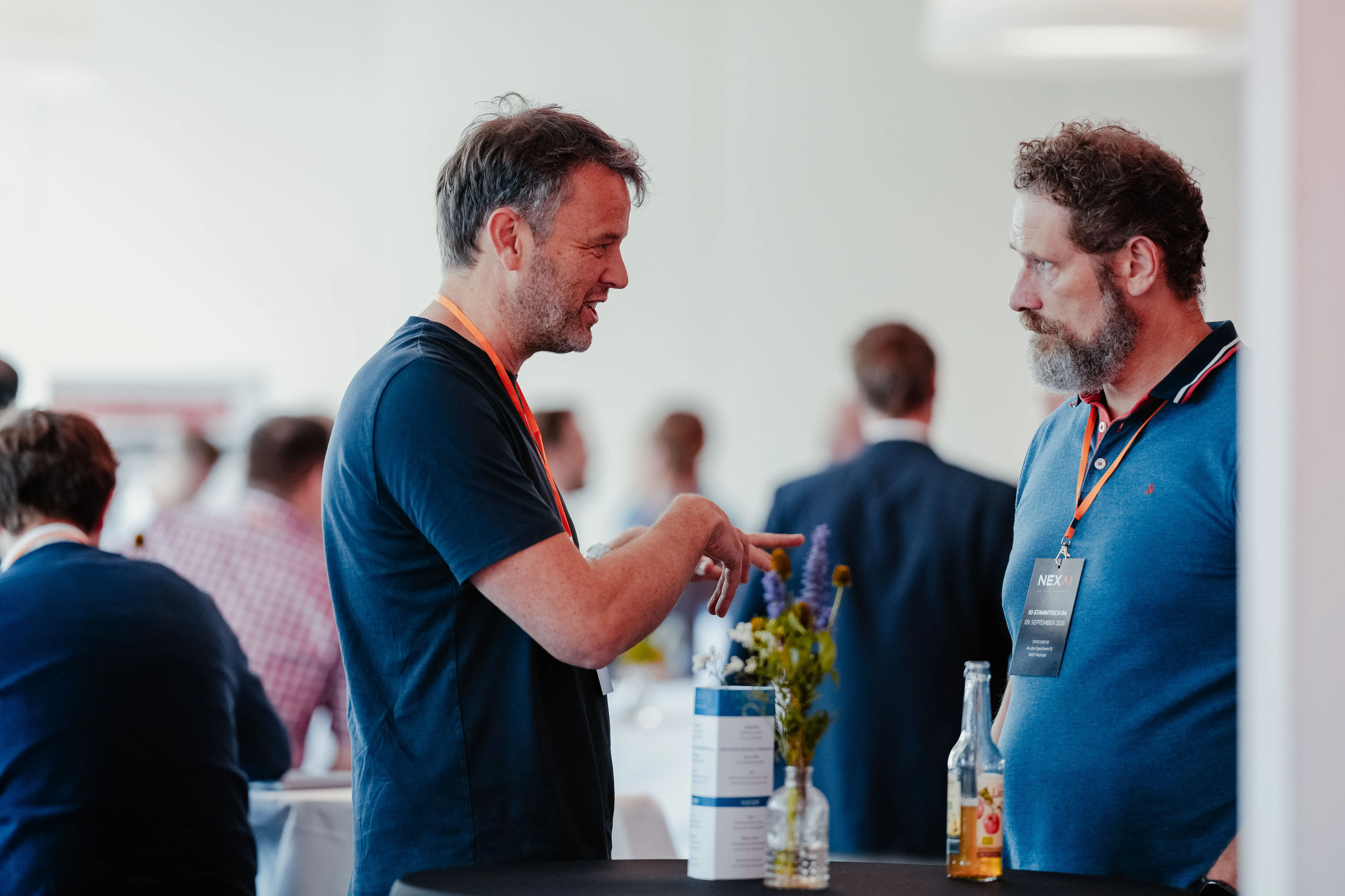 Zwei Gäste im Gespräch am Stehtisch beim NexAI KI-Stammtisch