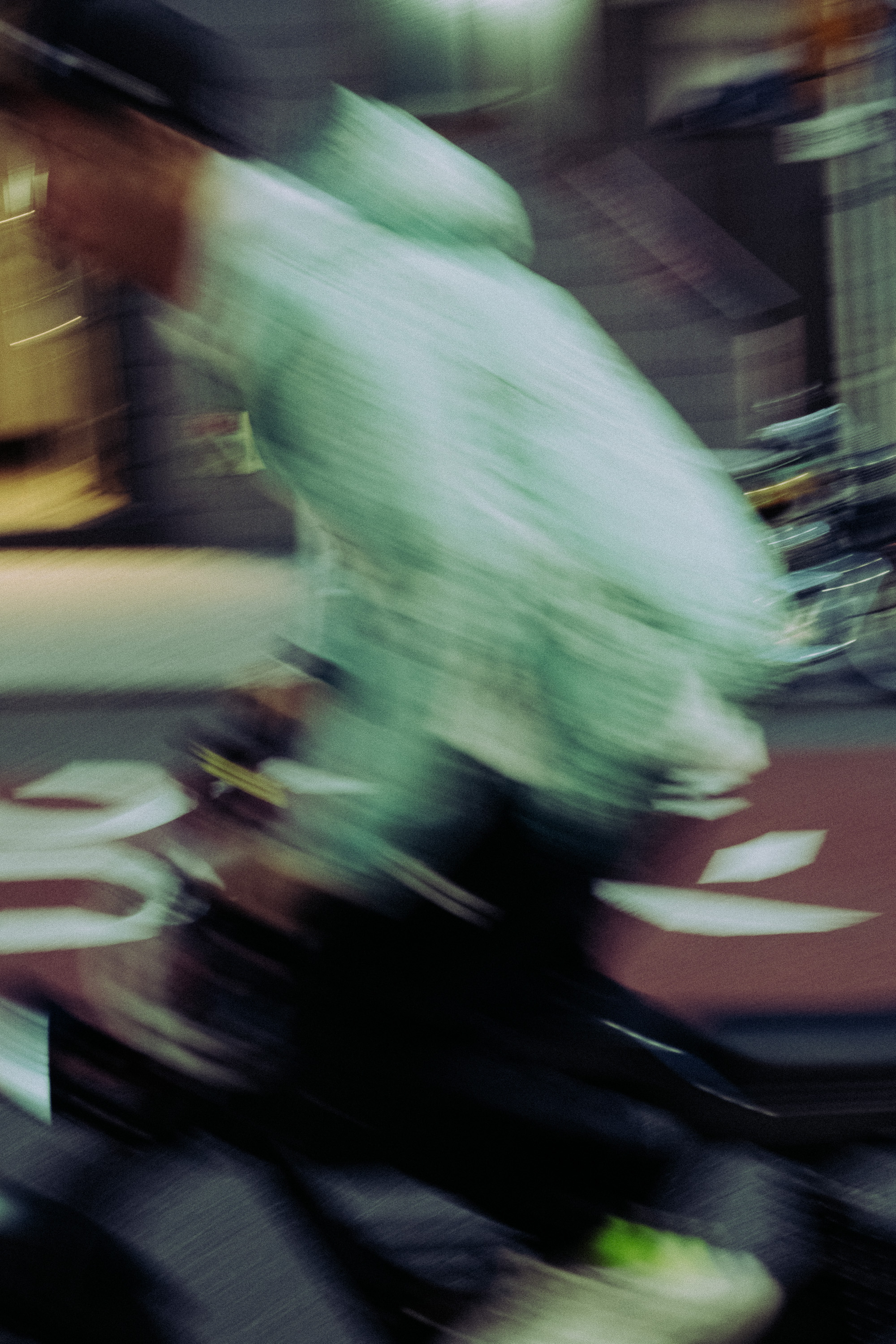 Blurred motion image of a person riding a bicycle on a street.
