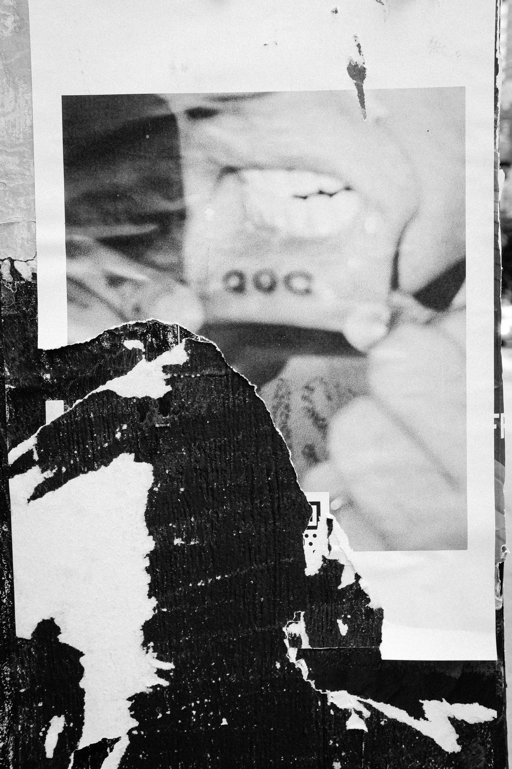 Black and white photo collage showing a close-up of a person's mouth with the word 'SOC' visible on the lower lip area, partially covered by torn black and white paper.