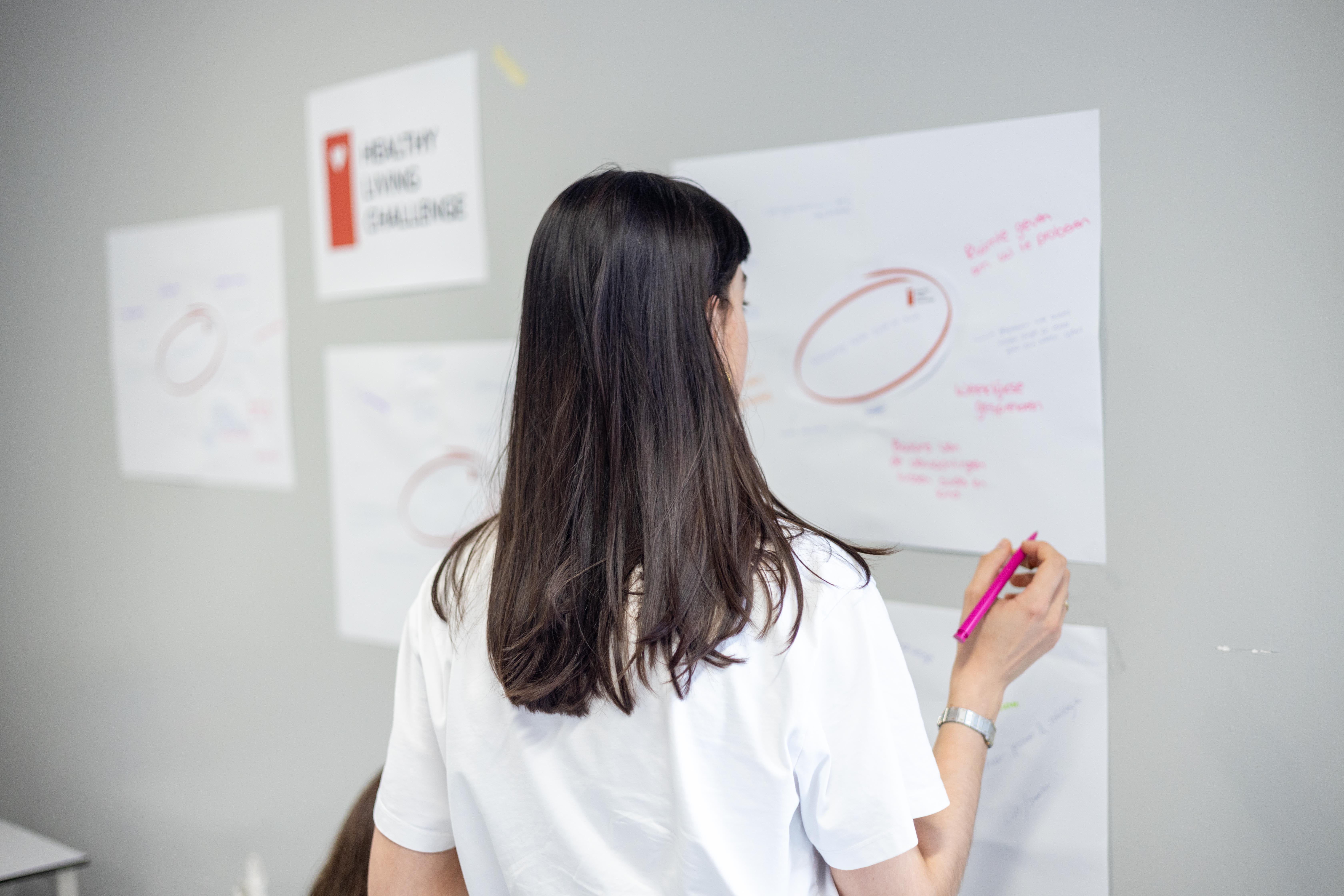Studente schrijft en tekent op vel papier op de muur