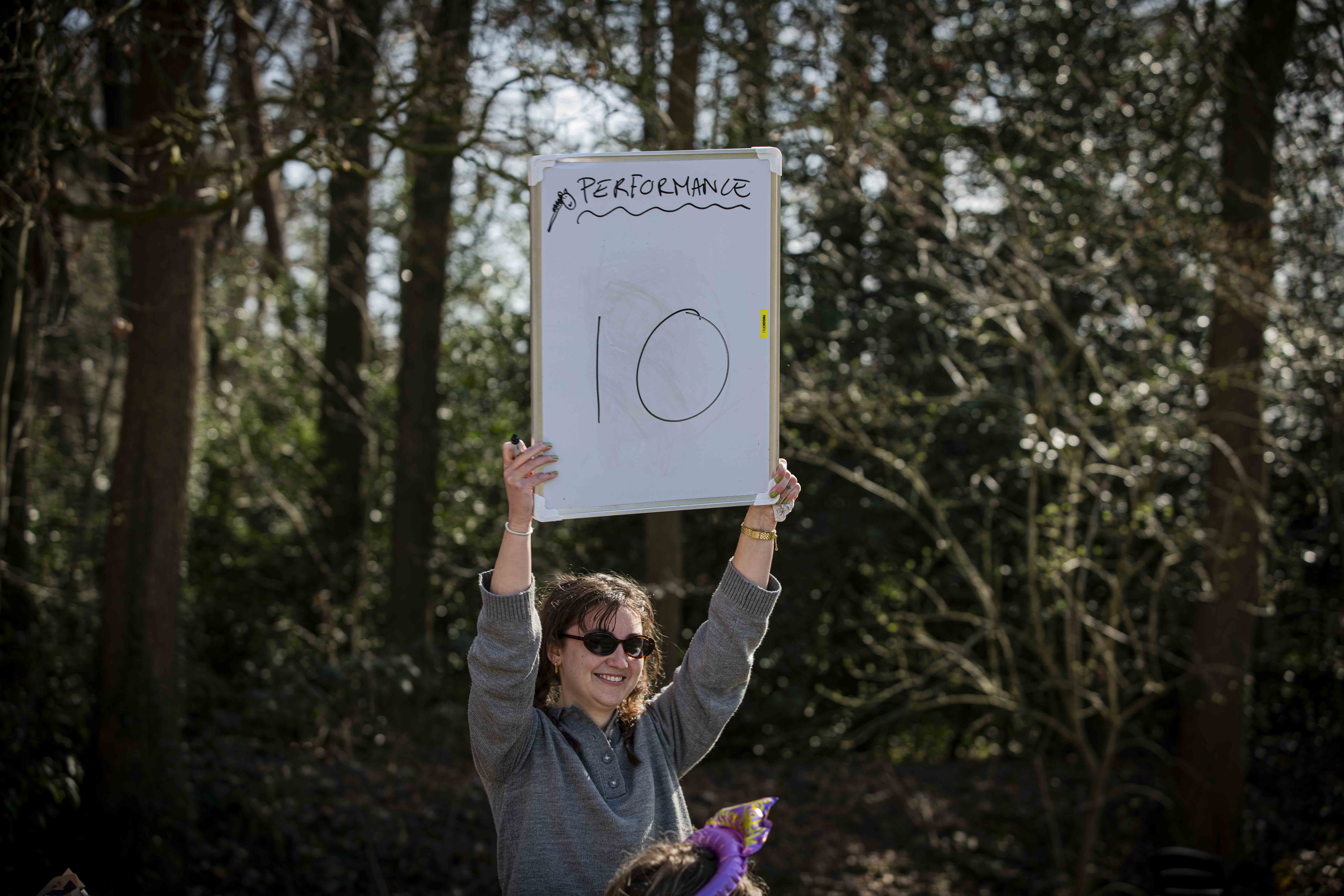 Vrouw houdt lachend een bord met een 10 omhoog