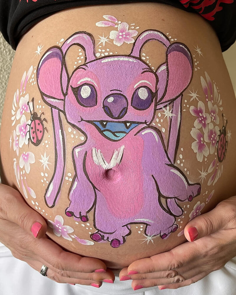 Een foto van een zwangere buik met een geschilderde afbeelding van Stitch.