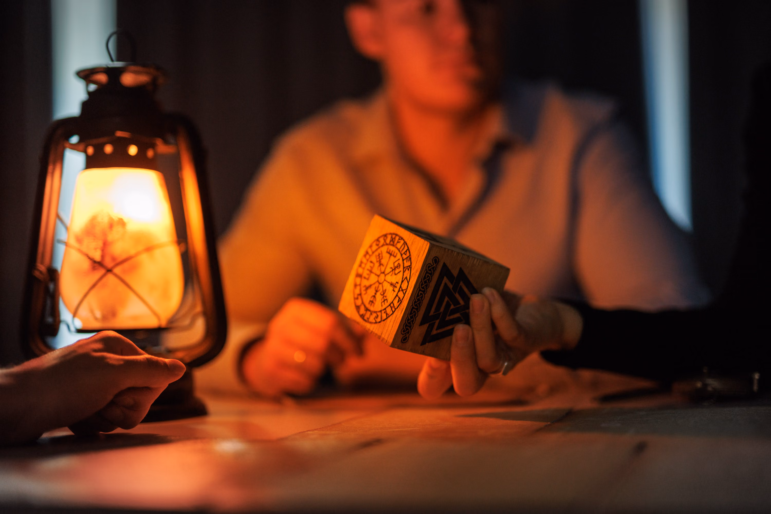 A man studies a strange rune covered cube lit by a lantern