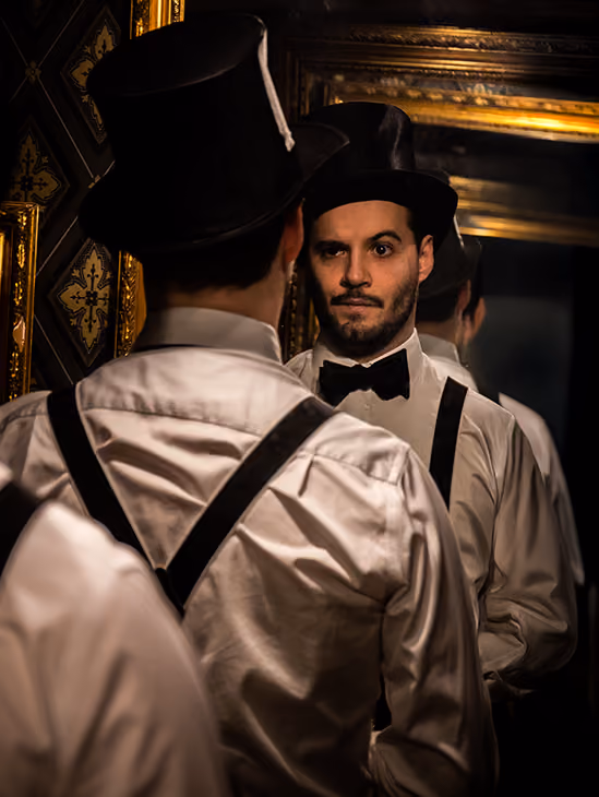A well dressed man stared into his own reflection in a mirro