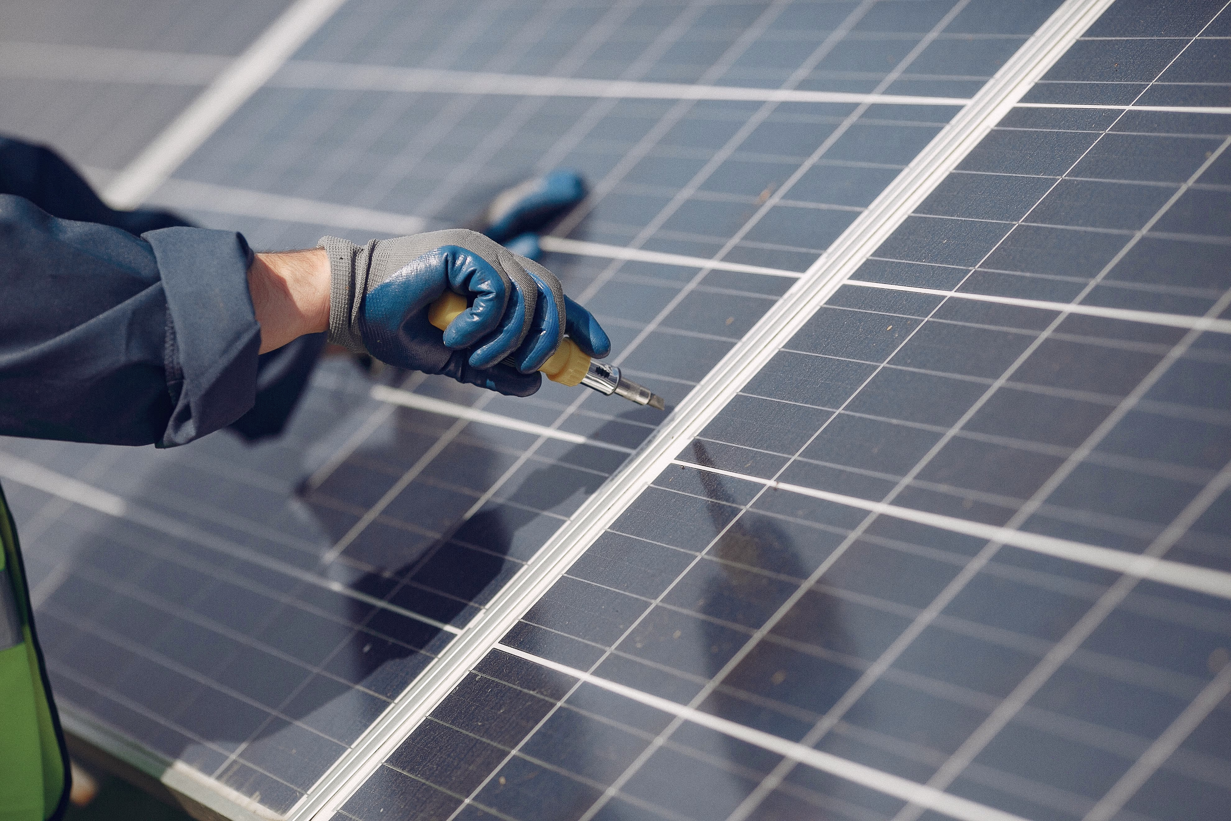 A person in blue gloves is working on a solar panel.