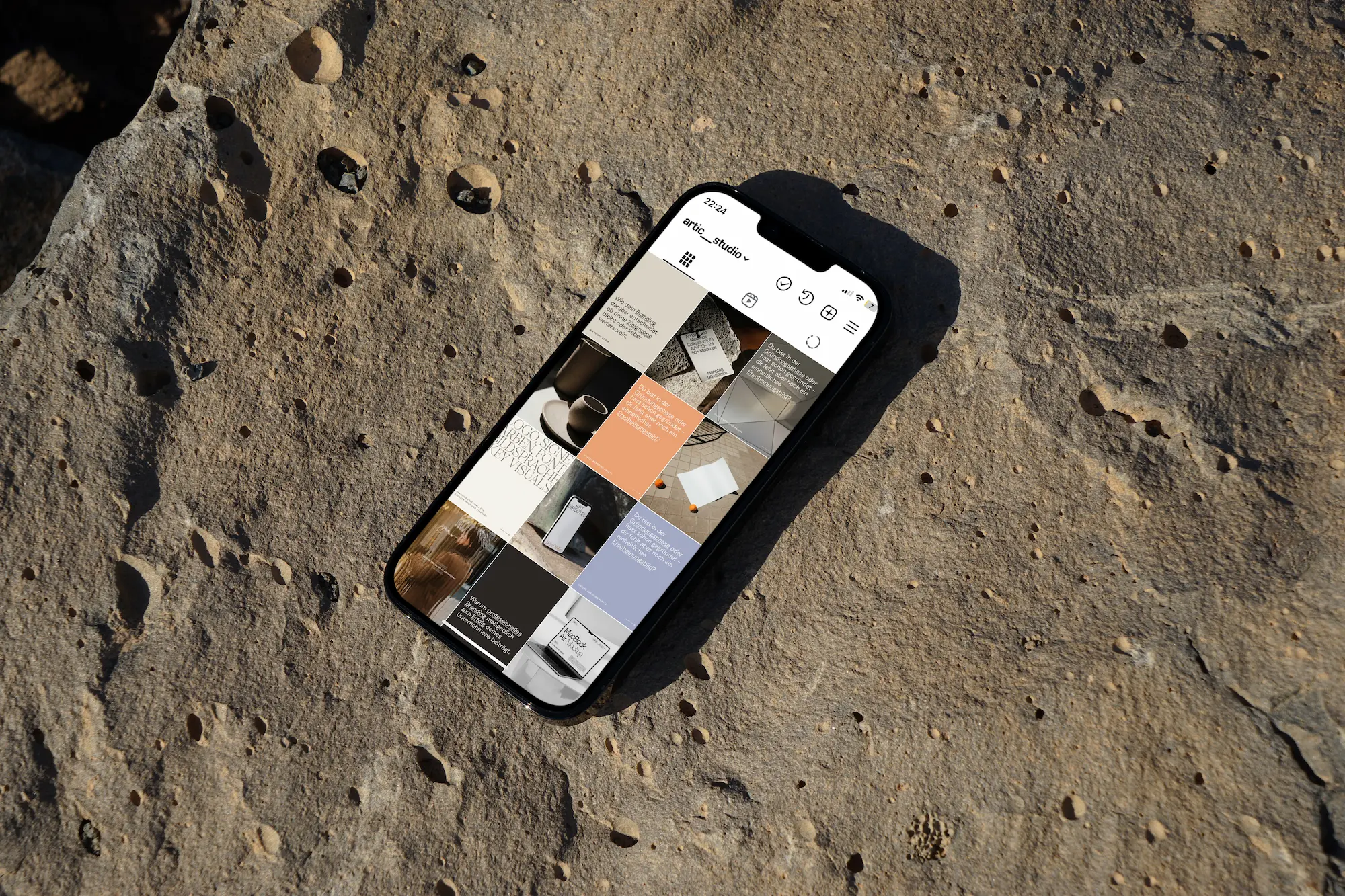 Smartphone, das ein Instagram-Profil mit einer Reihe von Beiträgen anzeigt, auf einer strukturierten felsigen Oberfläche platziert.