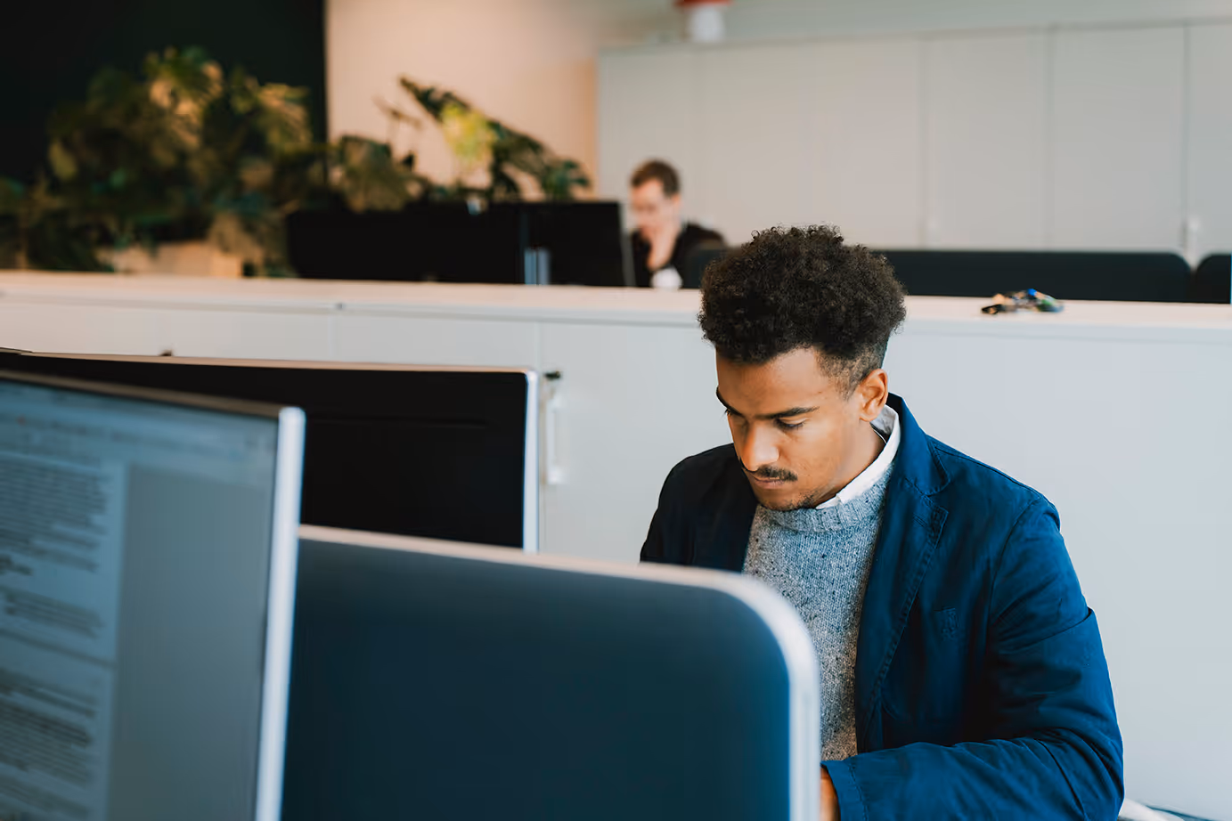 Young man focused on work at a computer in a modern office.