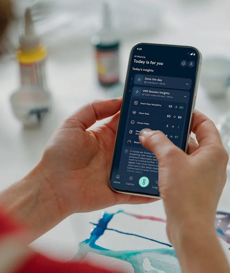 Person holding smartphone displaying health app with heart rate, stress index, and session insights.